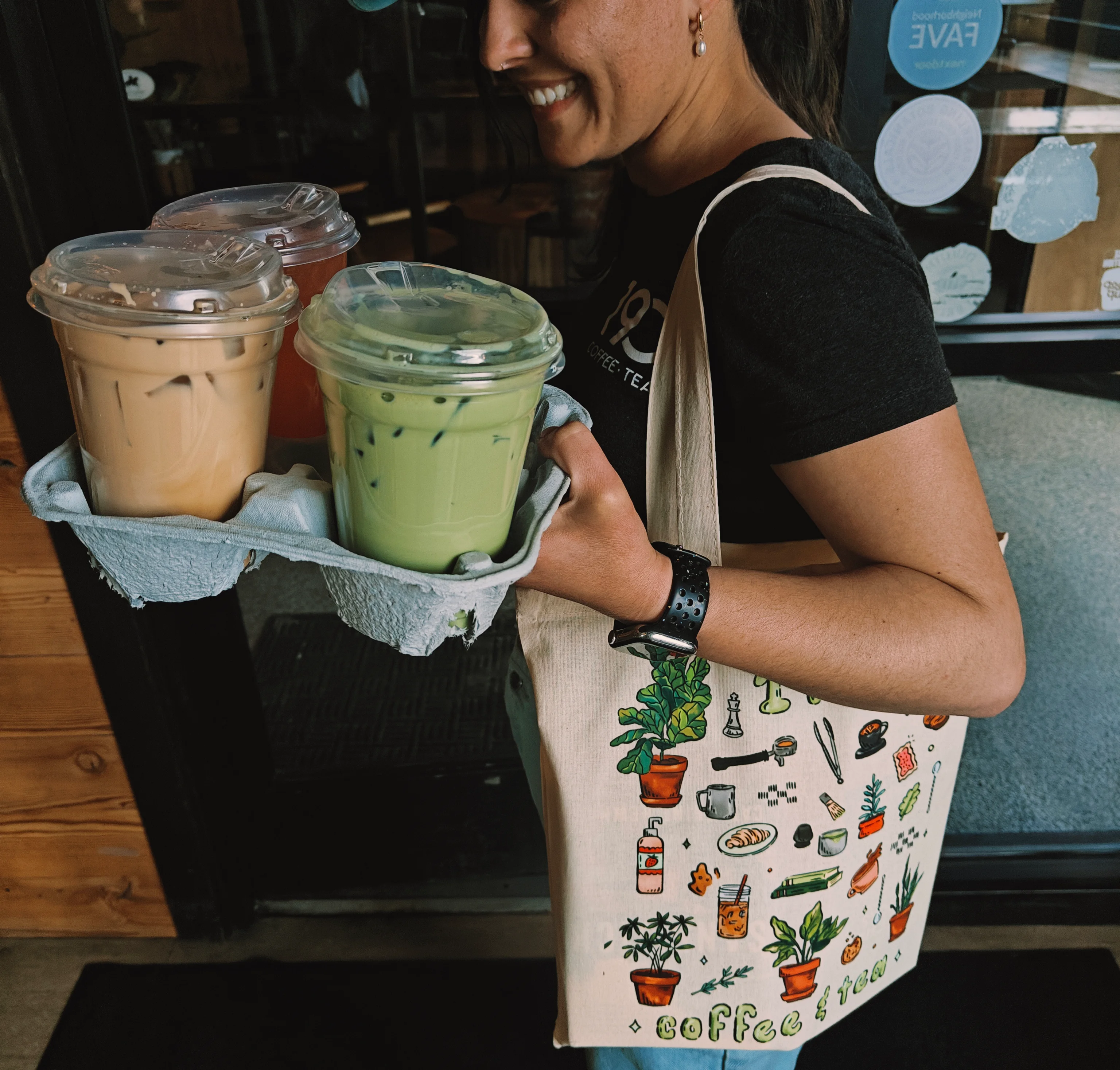 Person carrying iced drinks in a cozy café setting