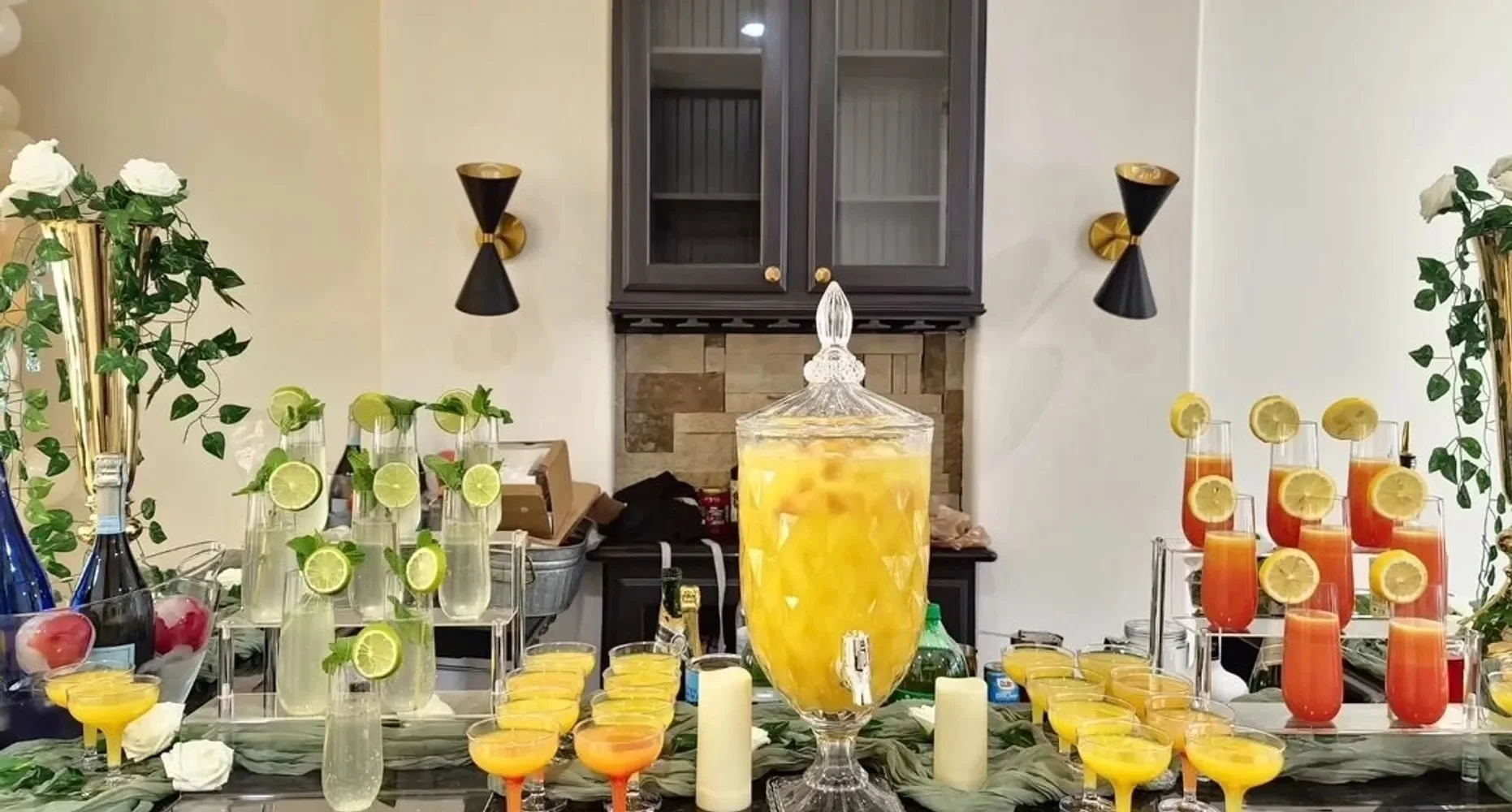 A stunning drink station with an array of colorful cocktails and a large pitcher of lemonade, complemented by decorative elements like flowers and lush greenery.