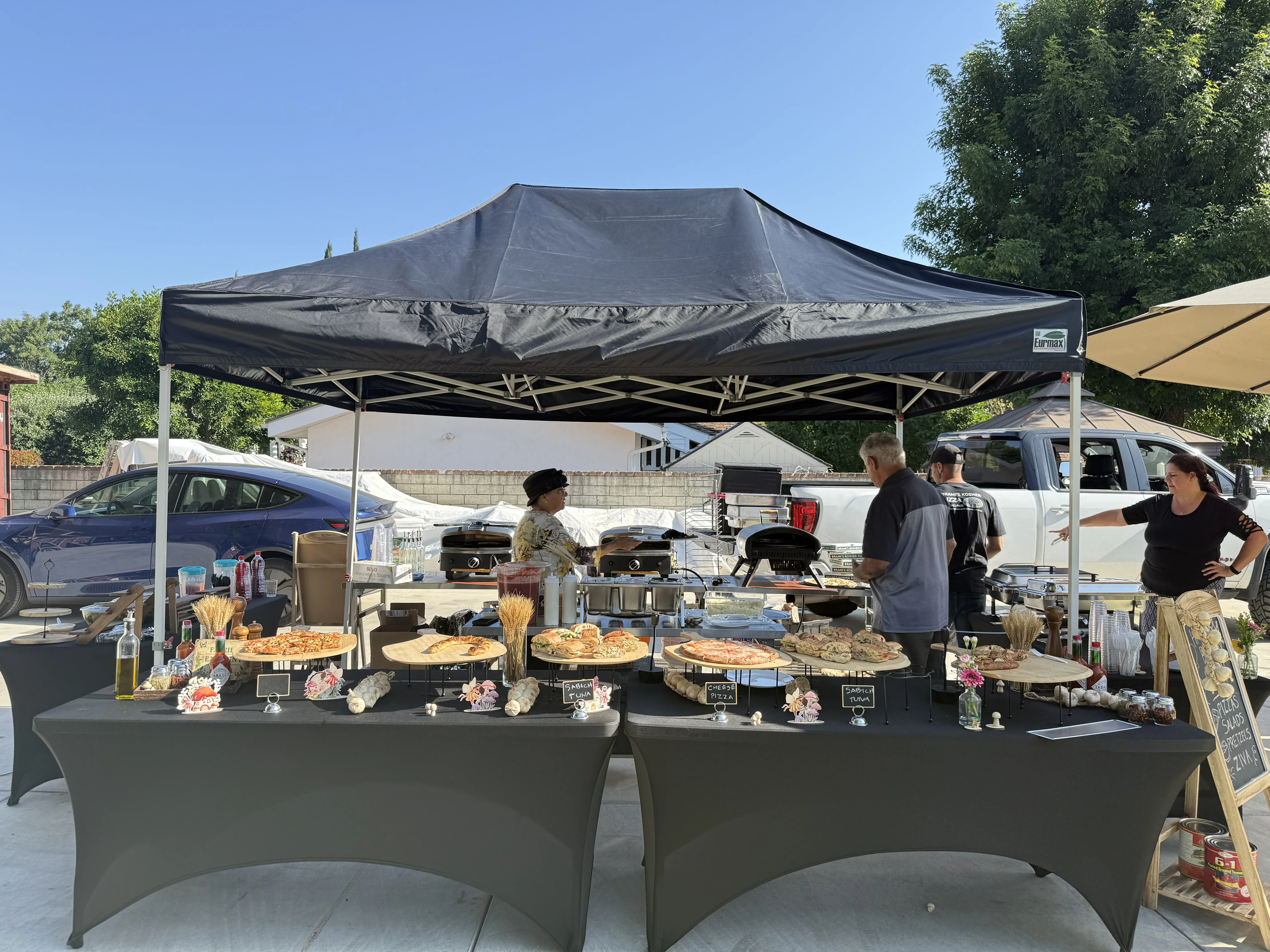 Outdoor food stall featuring a variety of pizzas and culinary displays