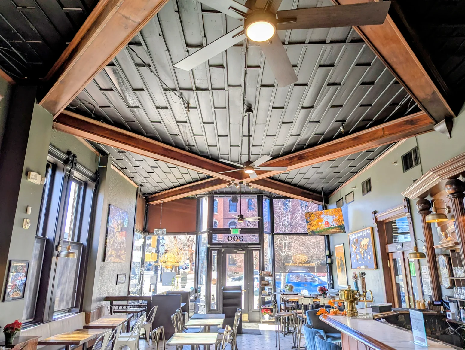 Bright restaurant interior with exposed beams, bar seating, and street-view windows