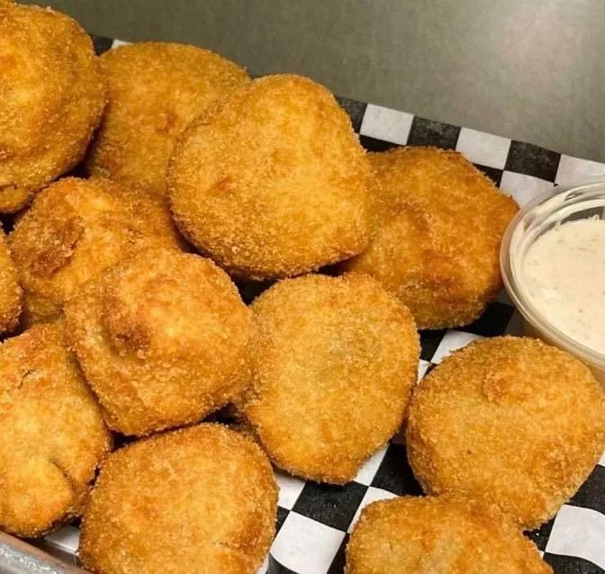 A platter of golden, deep-fried appetizers arranged neatly with a side of dipping sauce.