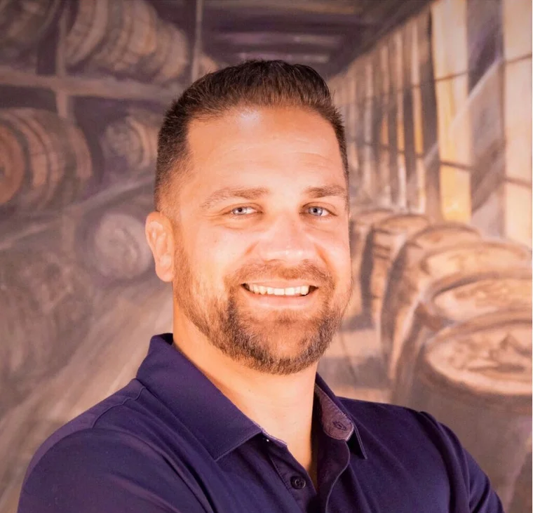 Smiling man in a restaurant with barrels in the background