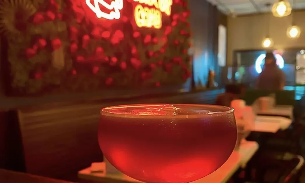 Craft cocktail in a stylish bar setting with neon lights
