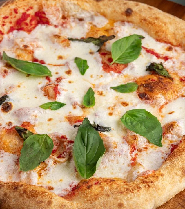 Brick oven Margherita pizza with fresh basil and melted mozzarella