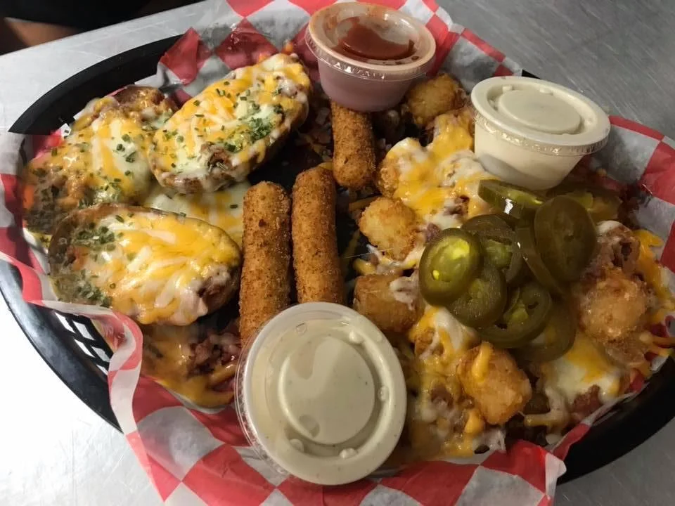 A plate of crispy, fried onion rings, arranged in a colorful basket with checkered paper.