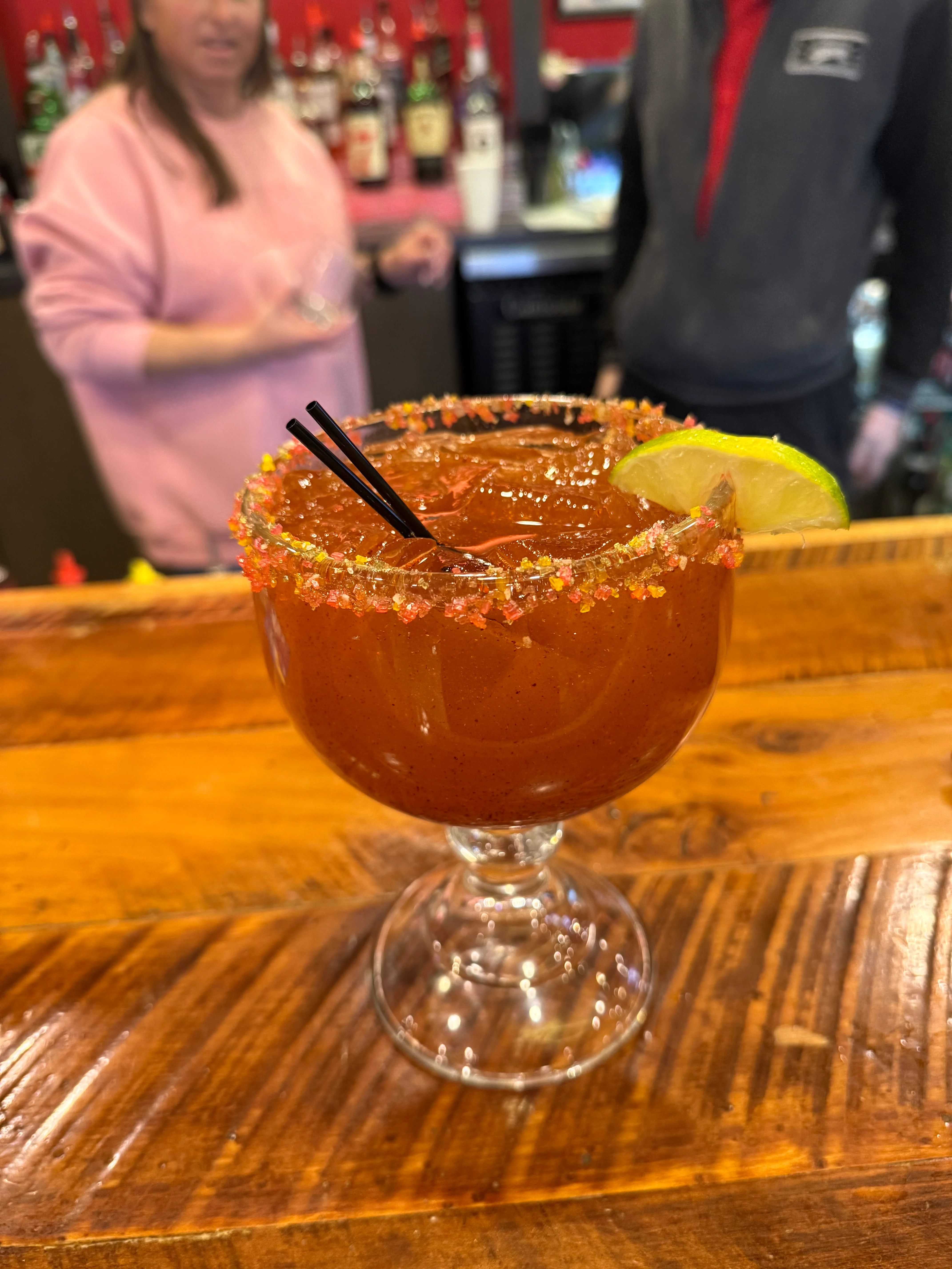 Colorful cocktail with lime and rimmed glass at a bar