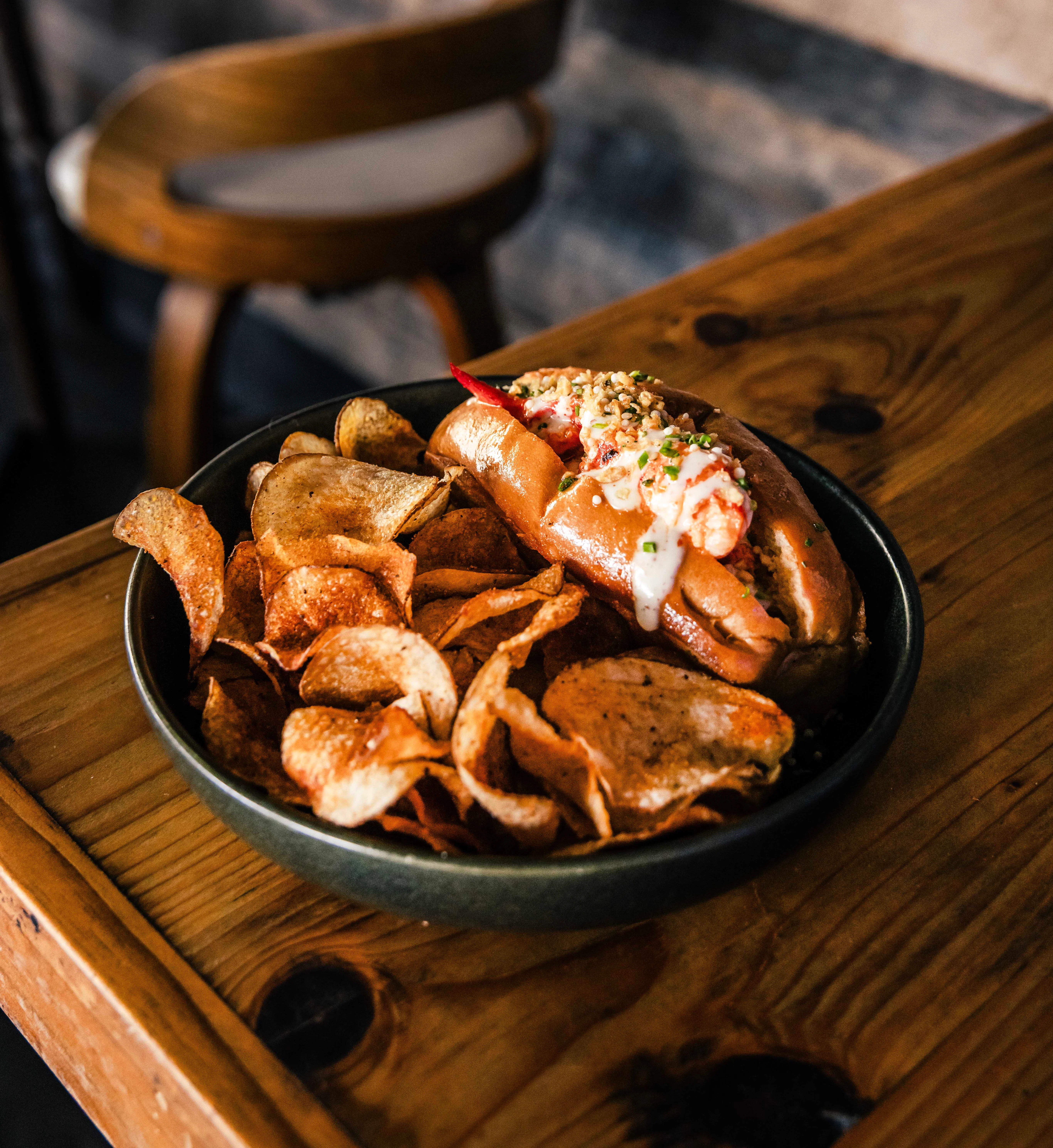 A plate of crispy fried shrimp arranged on a bed of fresh greens, including arugula and peas, with a charred lemon wedge.