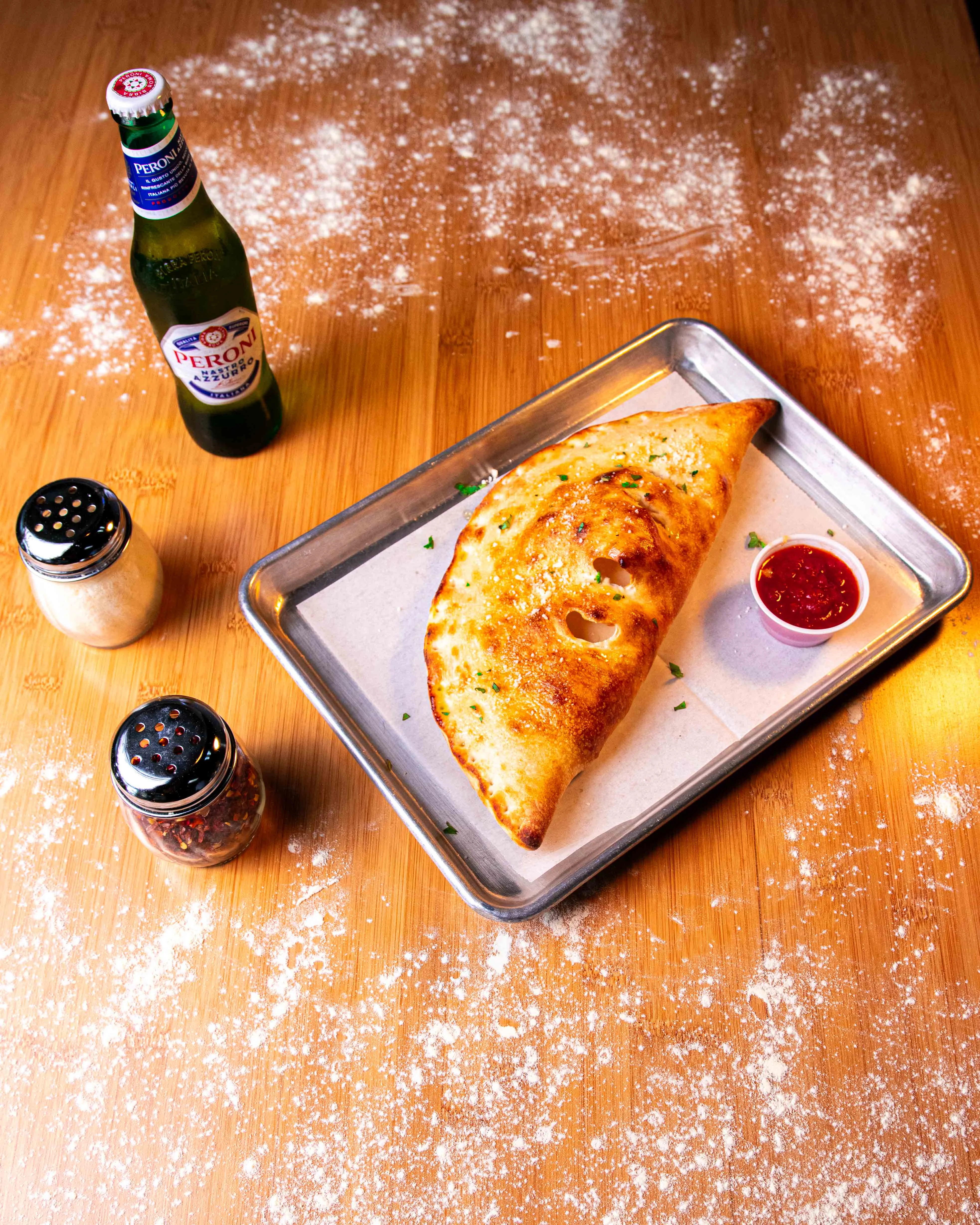 Golden calzone served with marinara sauce and a cold beer