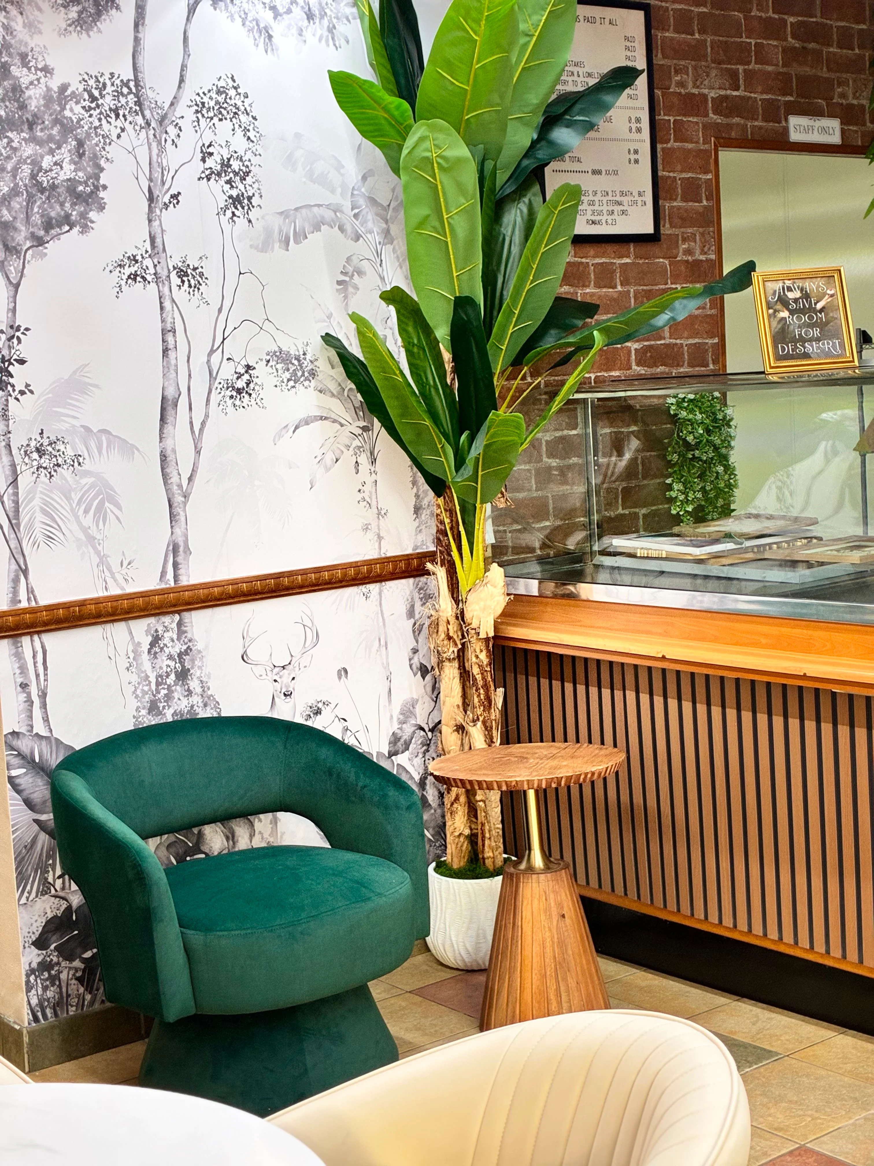 Restaurant interior with tropical plants, botanical mural, velvet seating, and brick accents