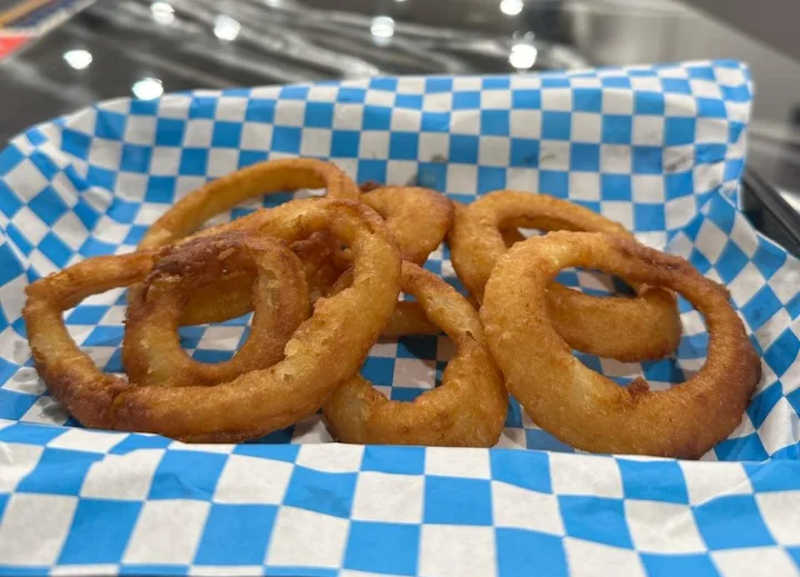 Crispy onion rings served in a blue checkered basket