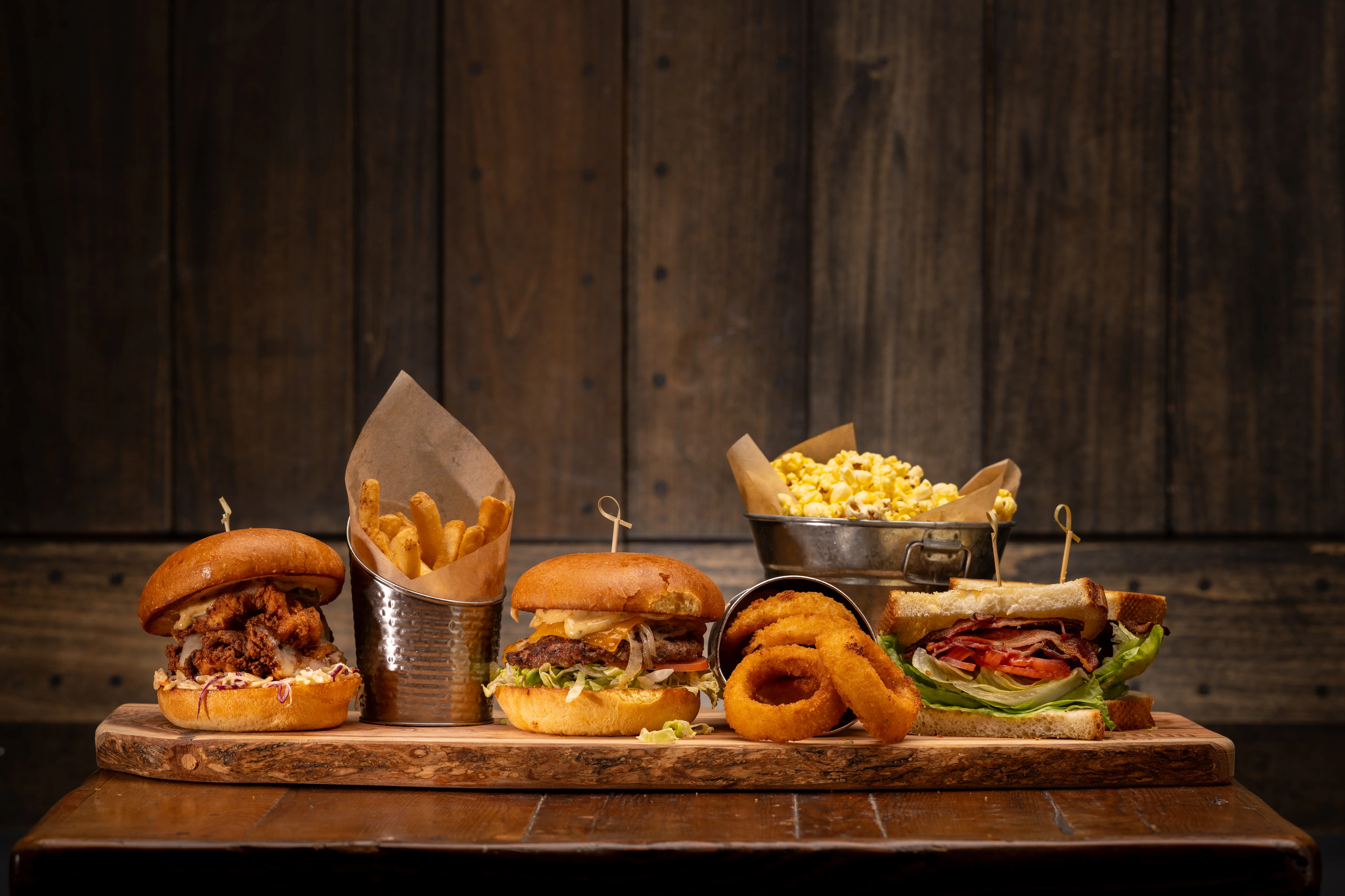 Assorted gourmet burgers with sides in a rustic setting