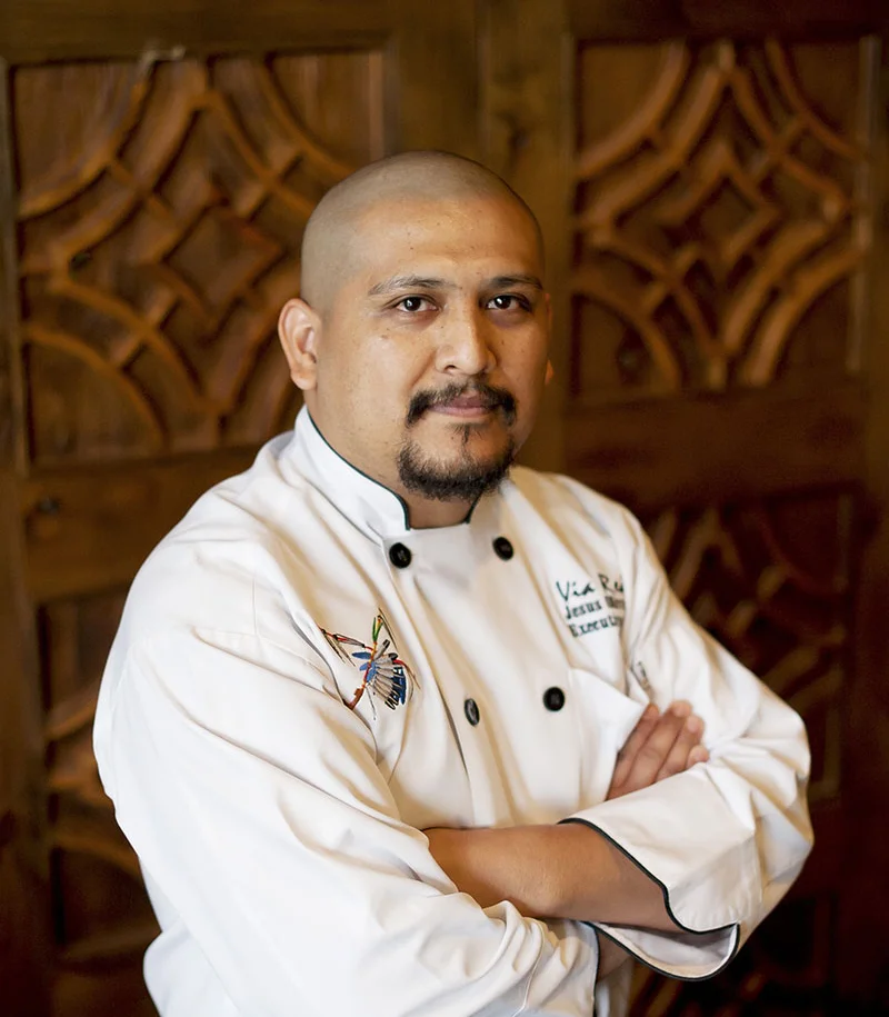 Chef in a white coat posing confidently in a restaurant setting