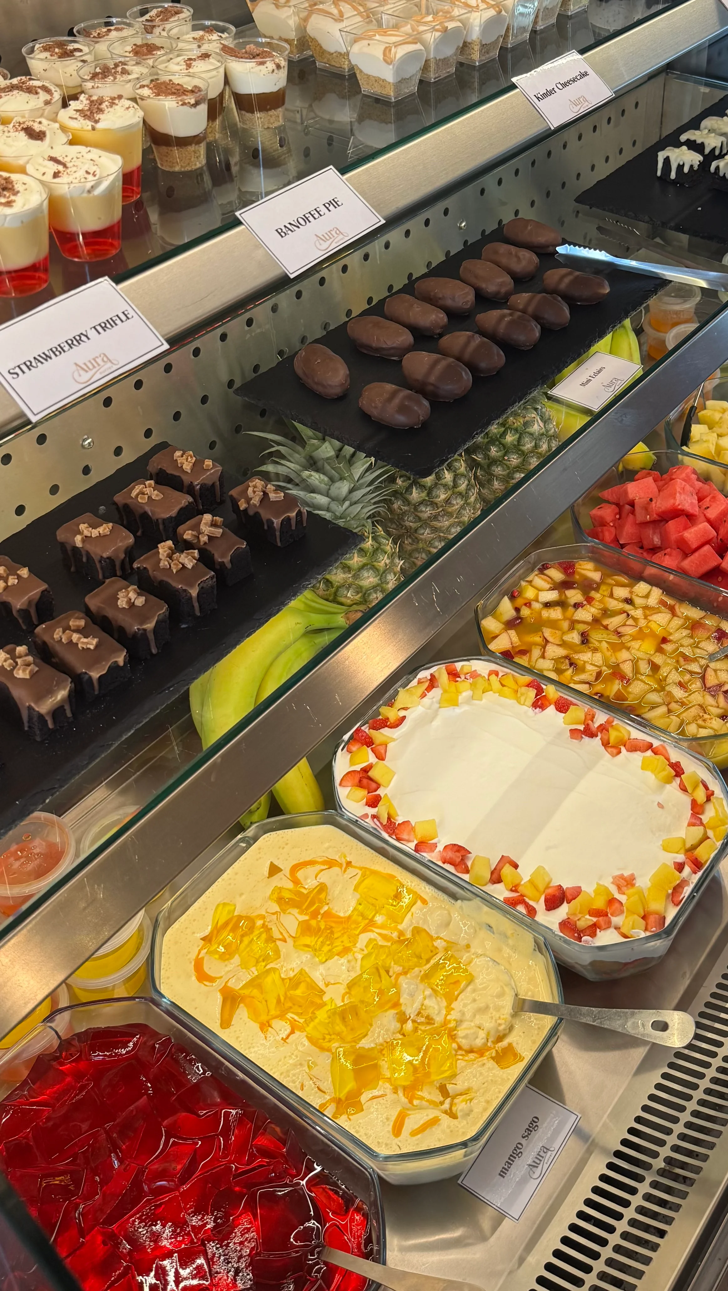 A display of assorted desserts including cakes, jellies, and fruits.