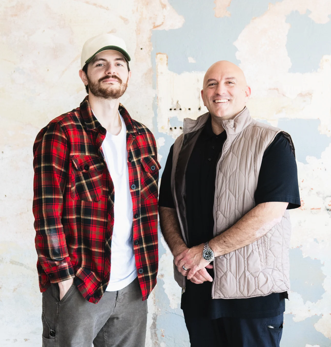 Two men posing in a rustic restaurant space with exposed walls