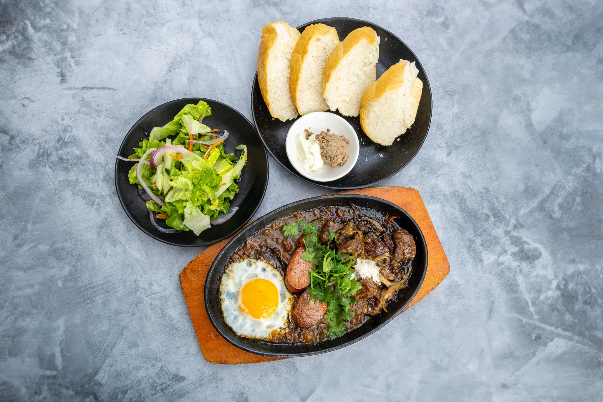 Sizzling beef steak with egg and salad on a hot plate