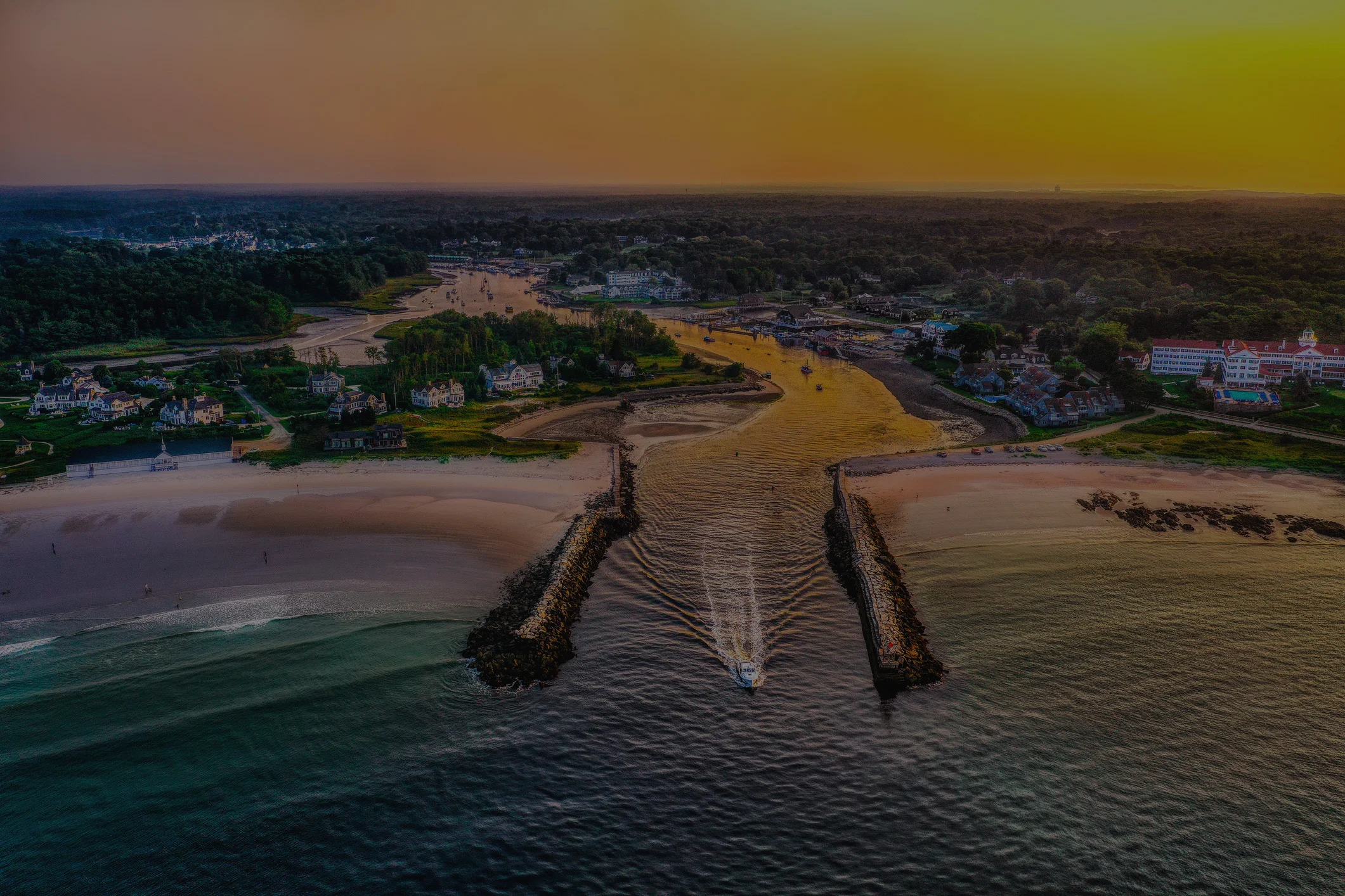 Aerial view of a coastal town at sunset with boats and sandy beaches