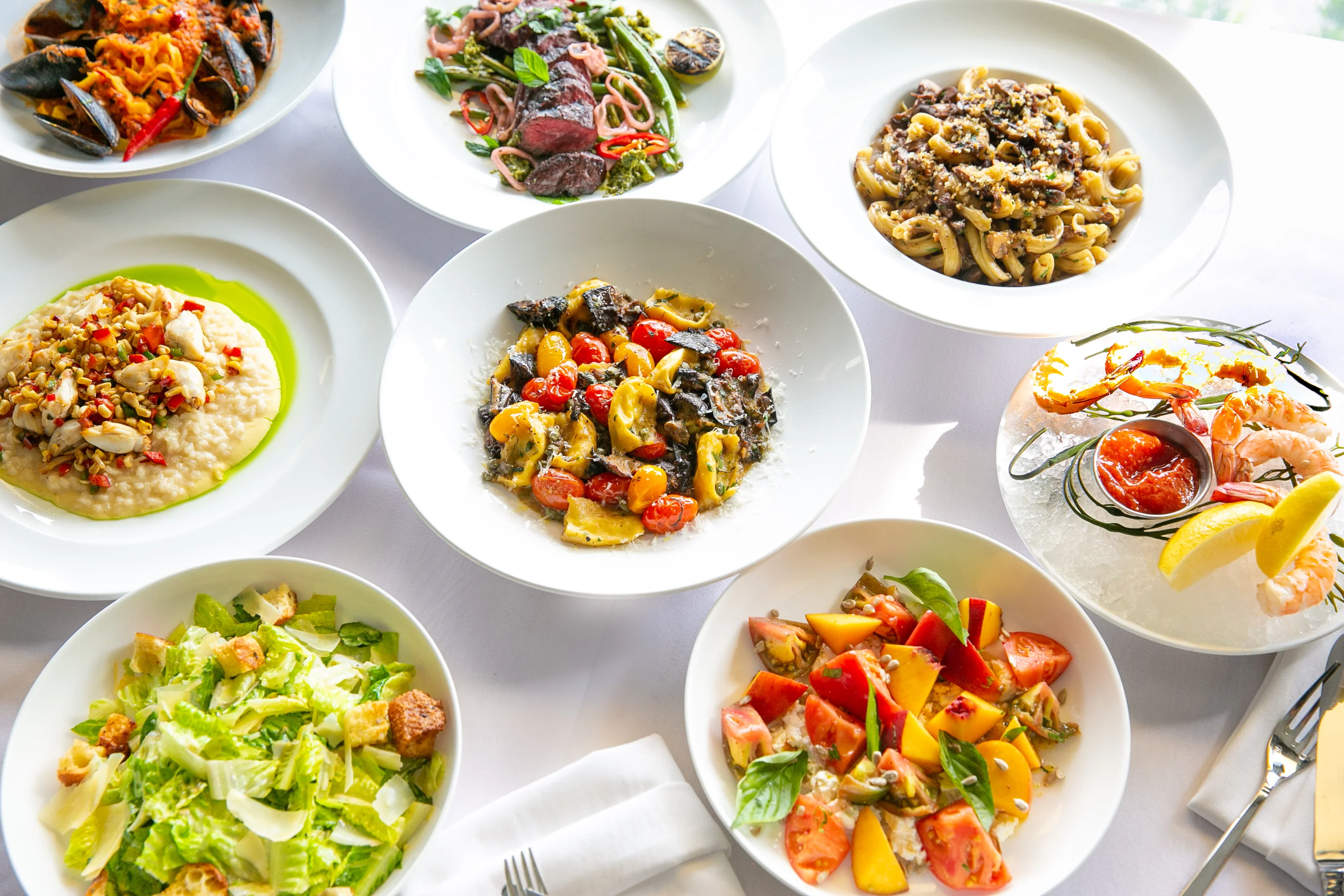 Assorted Italian pasta dishes and seafood platter on a white tablecloth