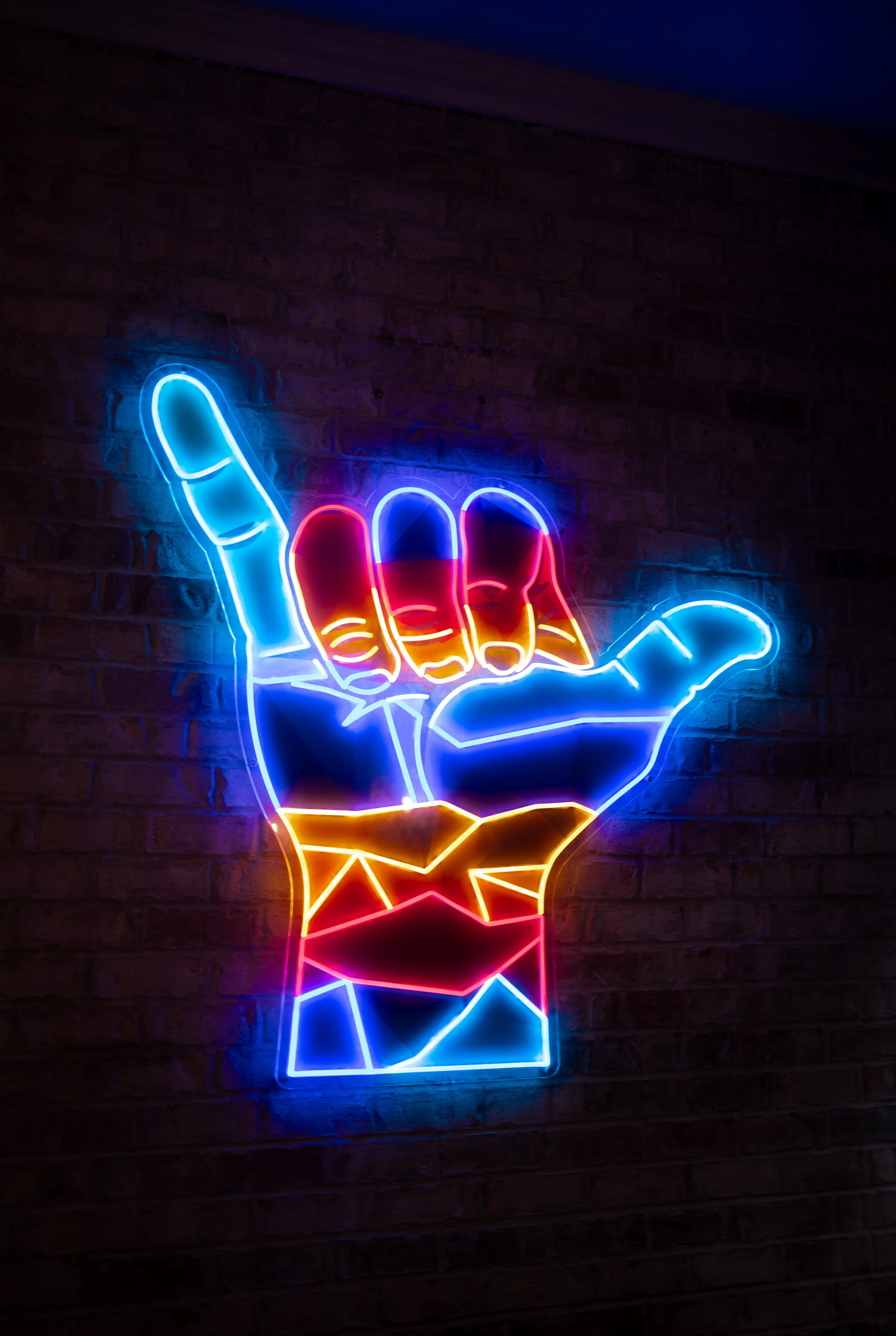 Colorful neon hand sign on a brick wall