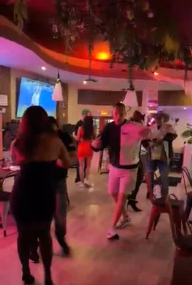 Vibrant restaurant scene with dancing patrons and colorful lighting