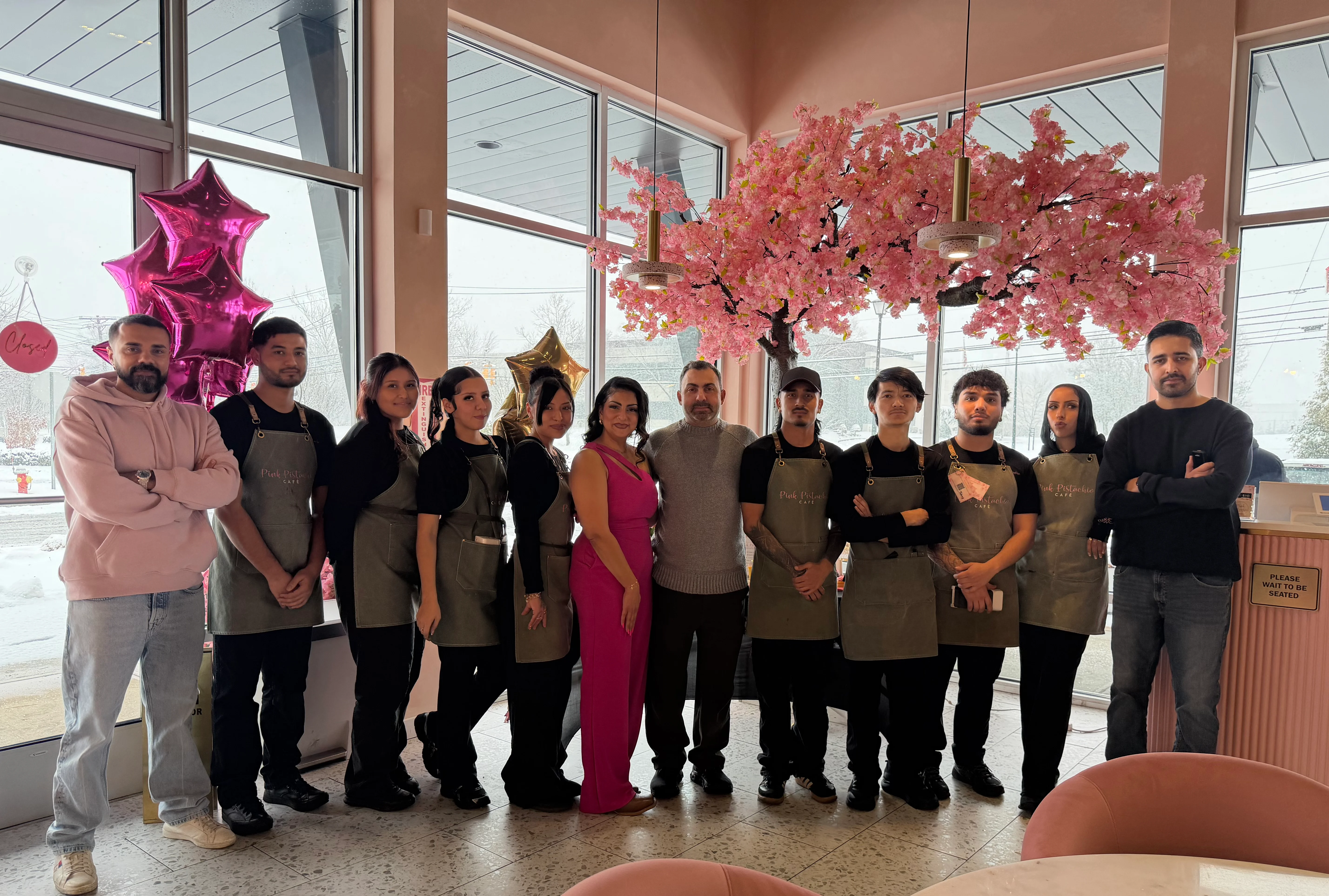 Restaurant staff posing in a cozy dining area with pink decor