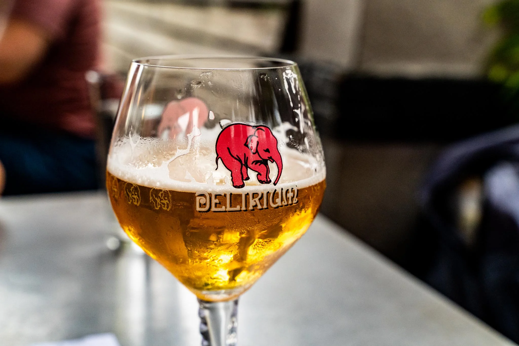 Glass of Belgian beer with a red elephant logo on a table