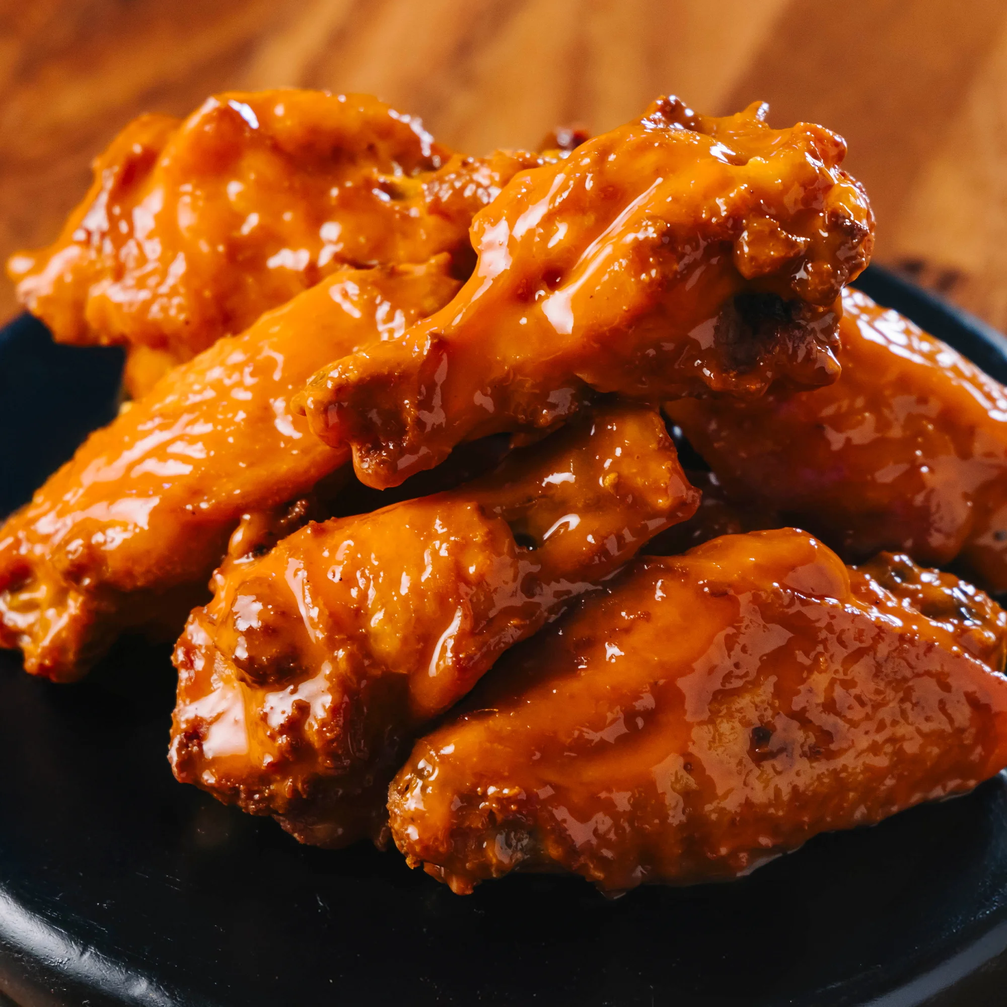 Crispy buffalo chicken wings served on a black plate