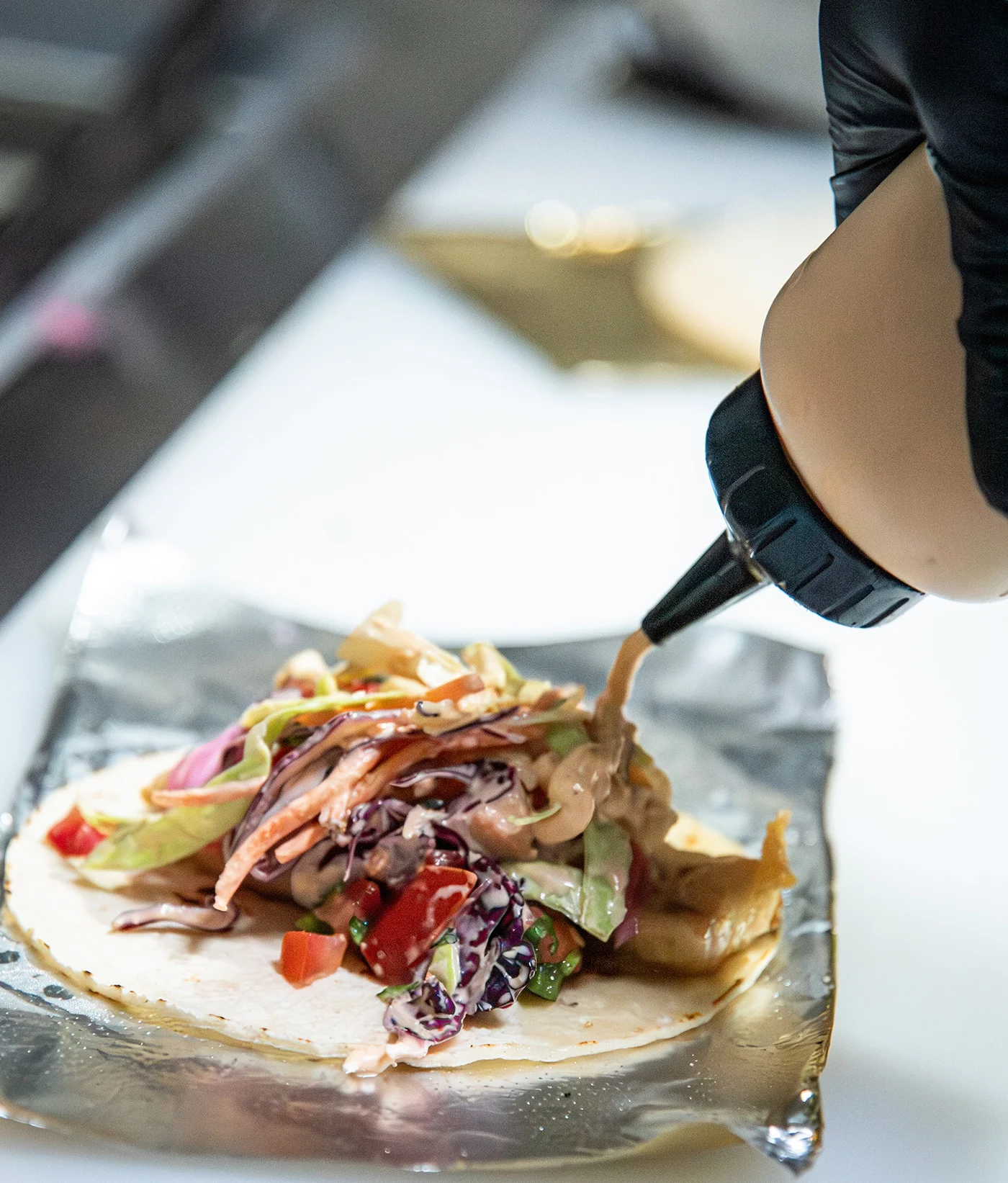 Crafting a fresh taco with colorful toppings and sauce
