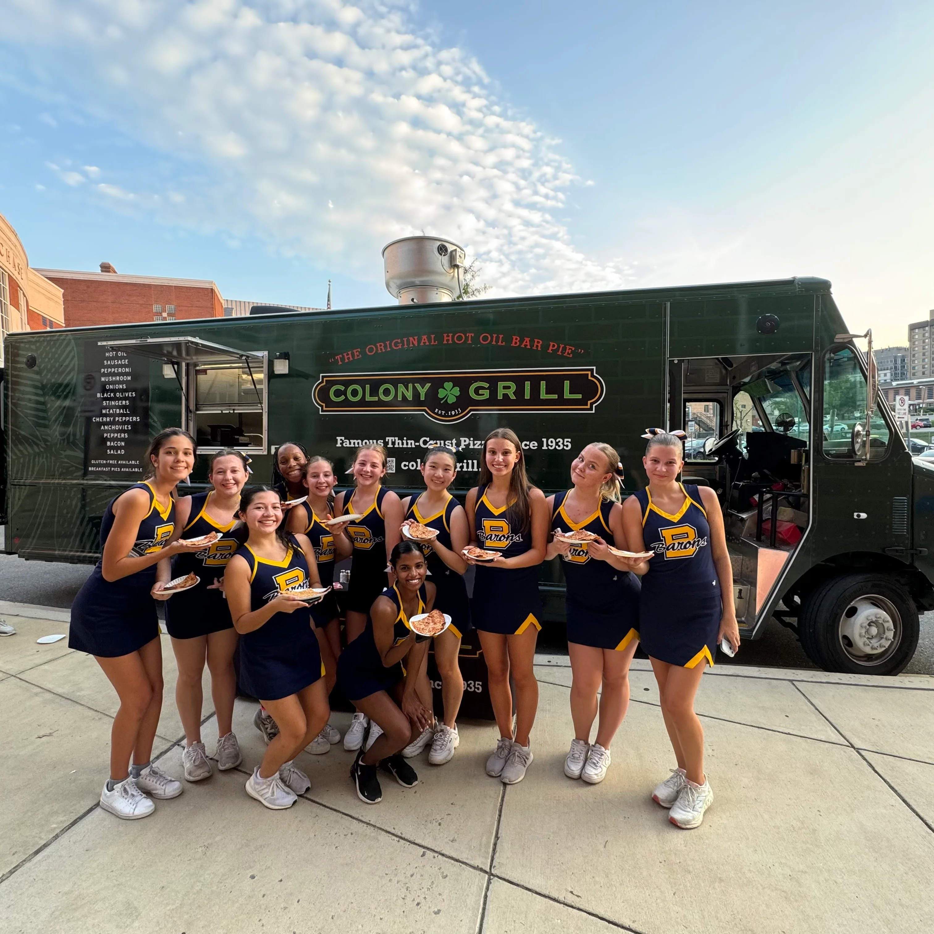 Cheerleaders enjoying Colony Grill pizza from a food truck
