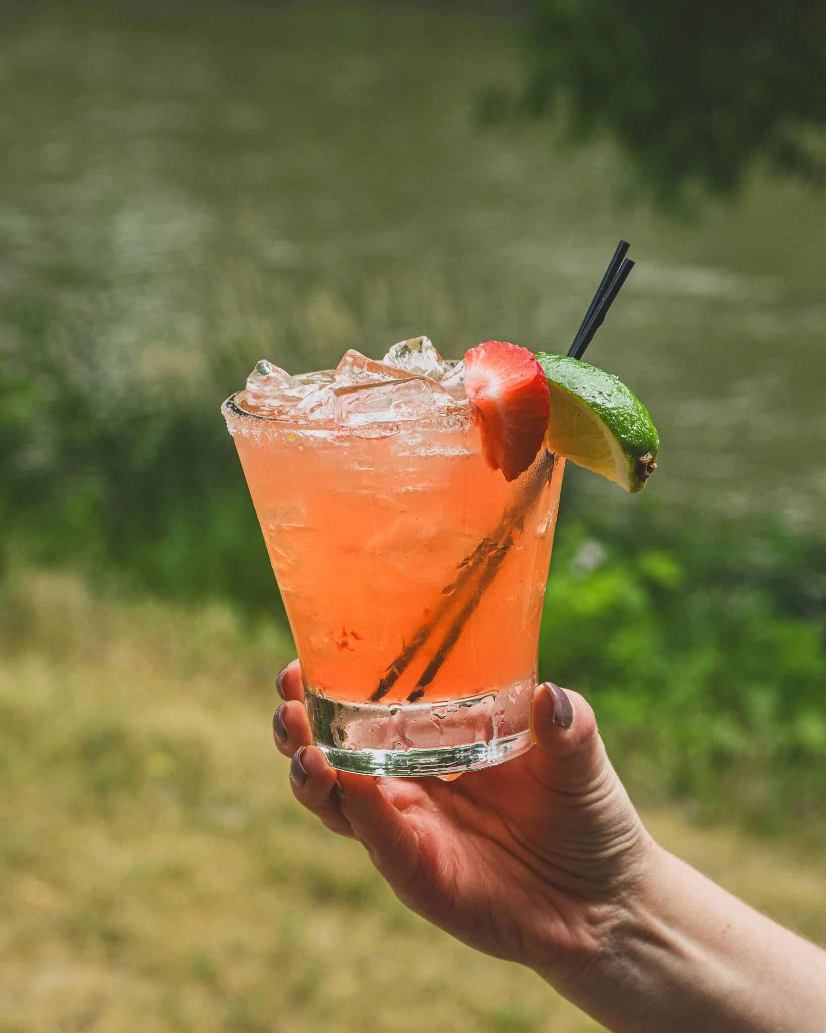 Strawberry Margarita held in front of the Baraboo River