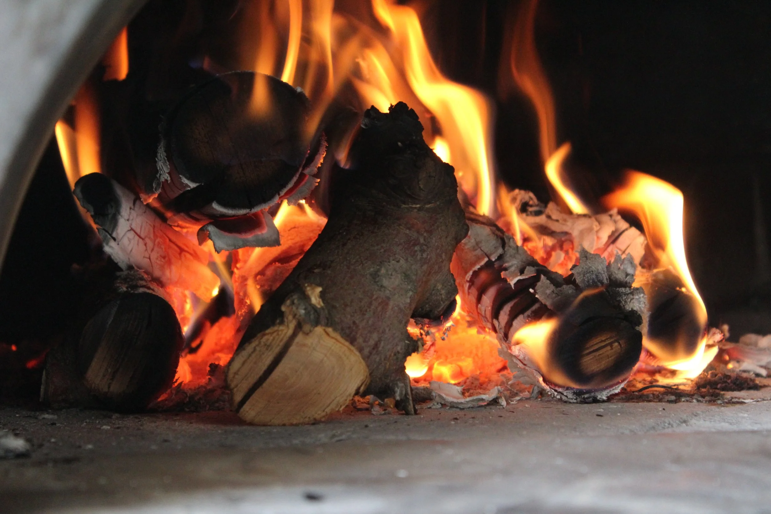 Wood-fired oven with burning logs for pizza