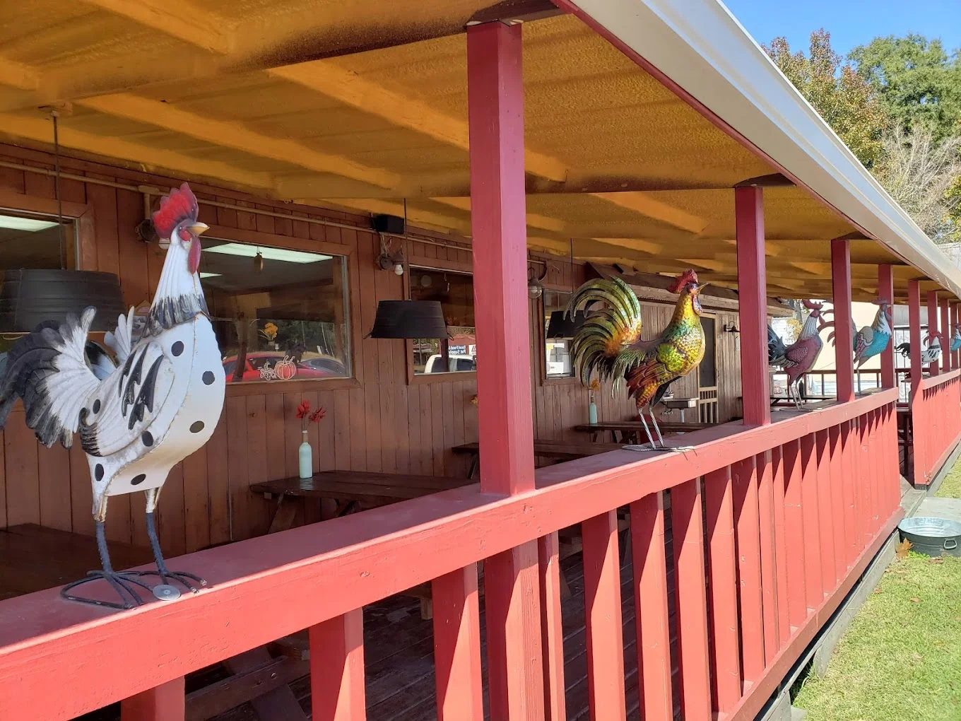Colorful metal roosters decorating a rustic restaurant patio
