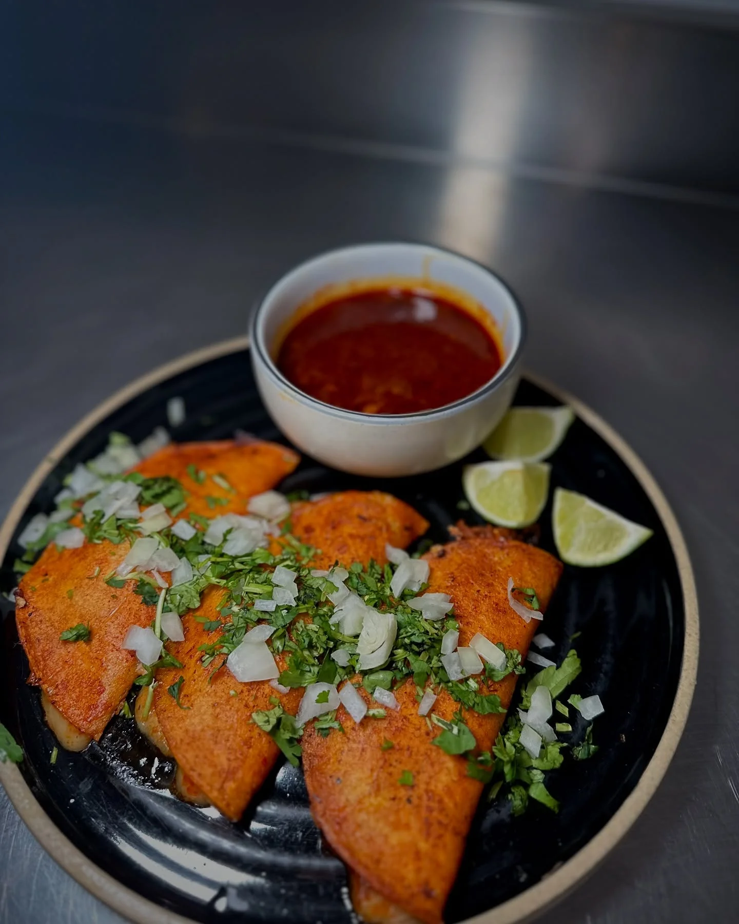 Delicious Mexican quesabirrias with salsa and lime wedges