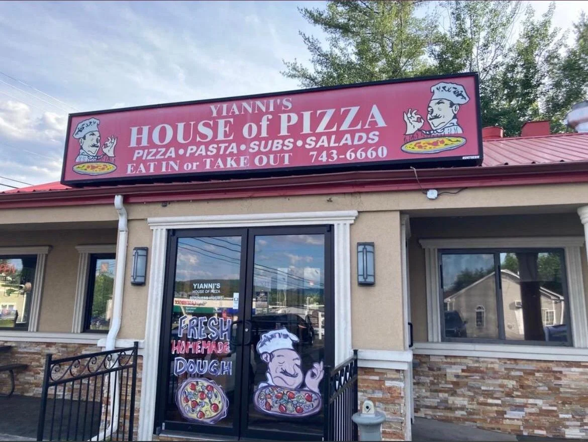 Exterior view of a pizza restaurant with a red roof and parking area.