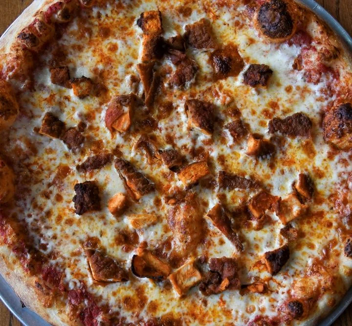 A cheese pizza topped with pieces of cooked meat, showing a golden-brown crust and melted cheese.