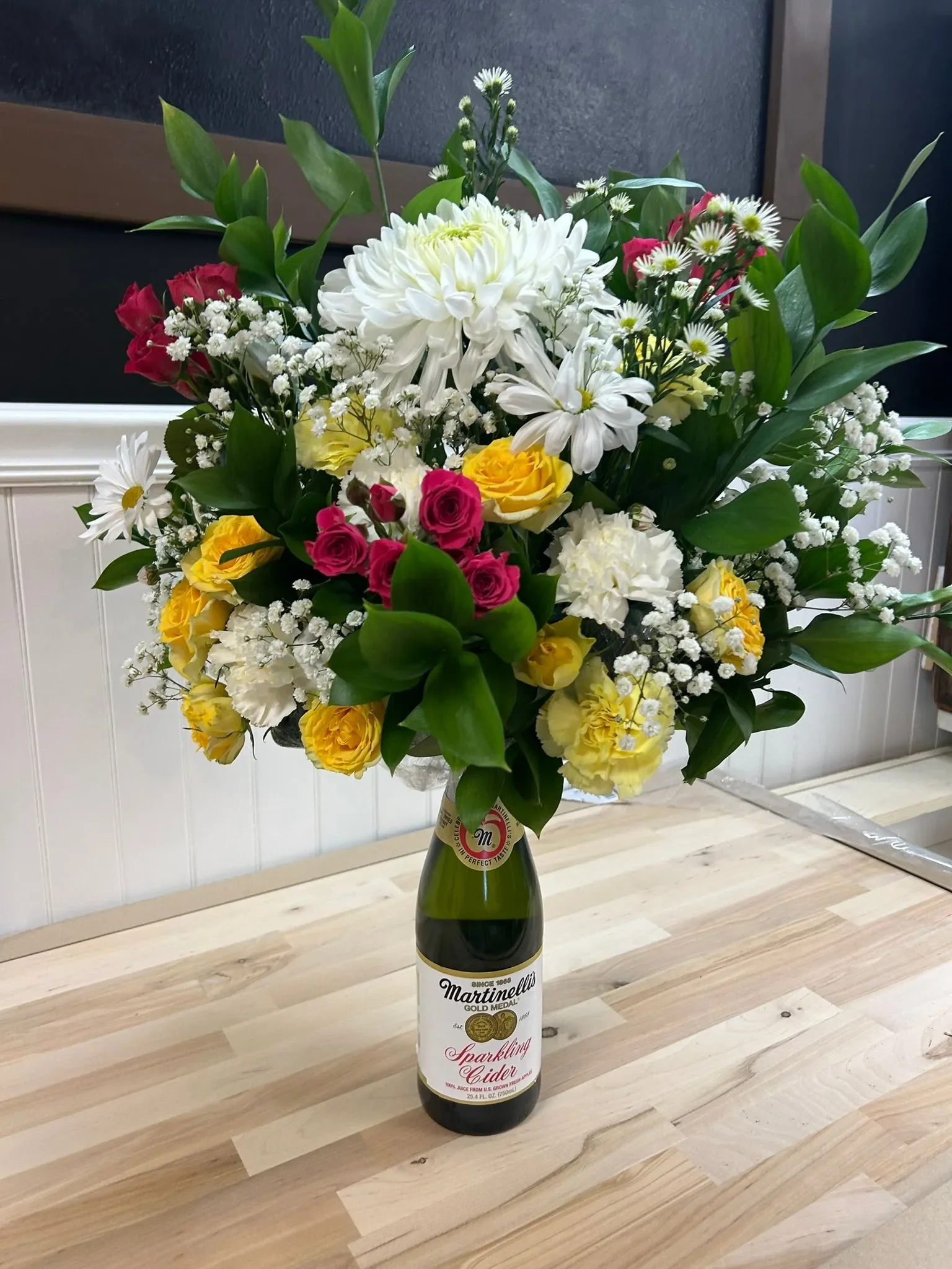 Vibrant floral arrangement in a sparkling cider bottle