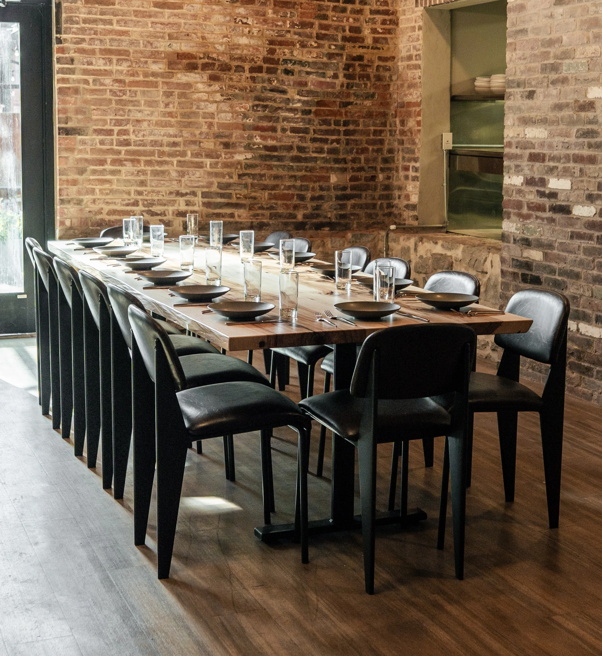 Stylish restaurant dining area with long wooden table and black chairs