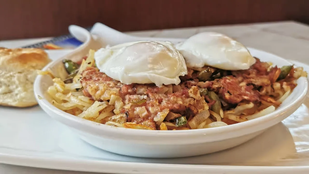 Moonlite Diner corned beef hash with crispy hash browns, poached eggs, peppers, onions, and a freshly baked biscuit.