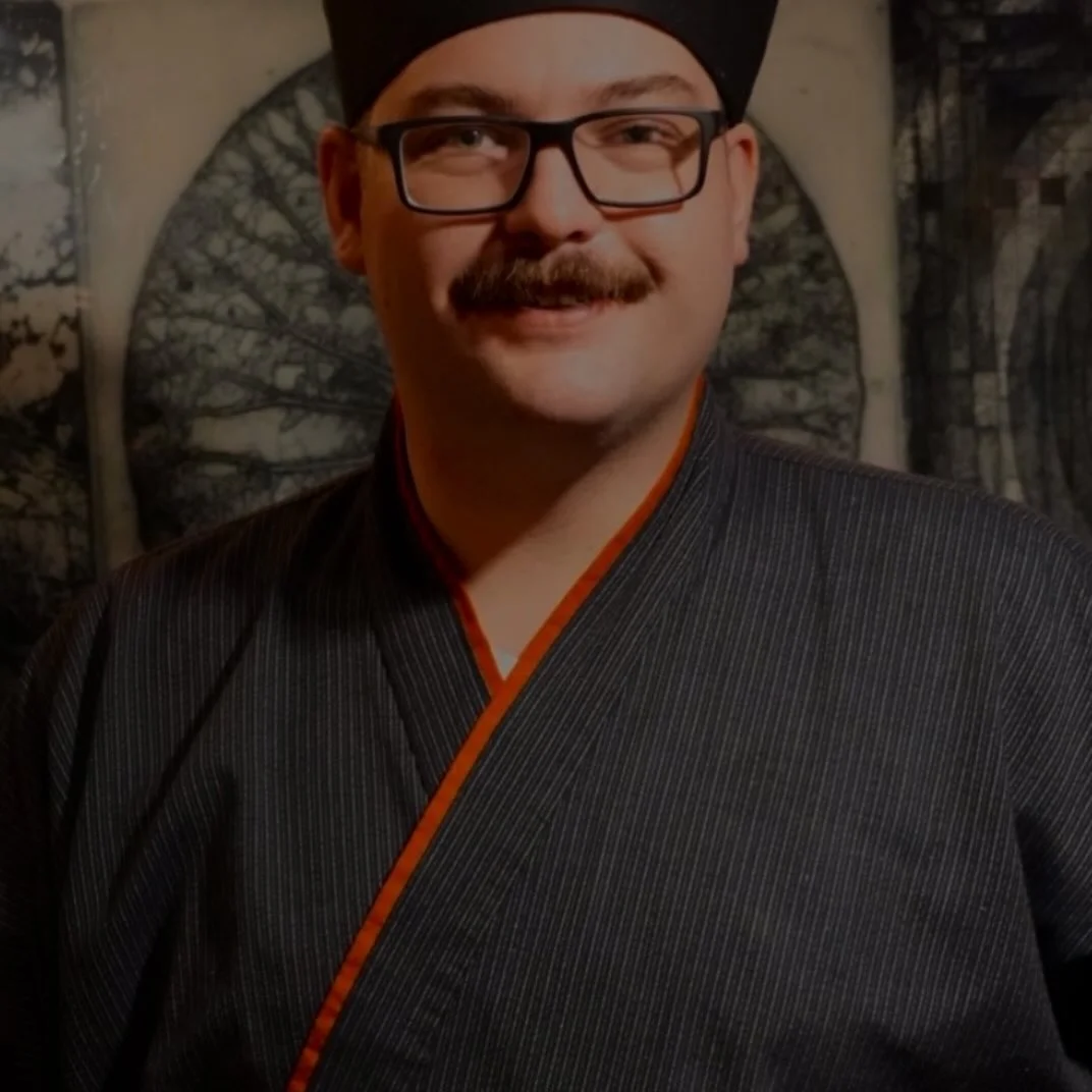 Chef in traditional Japanese attire with a warm smile