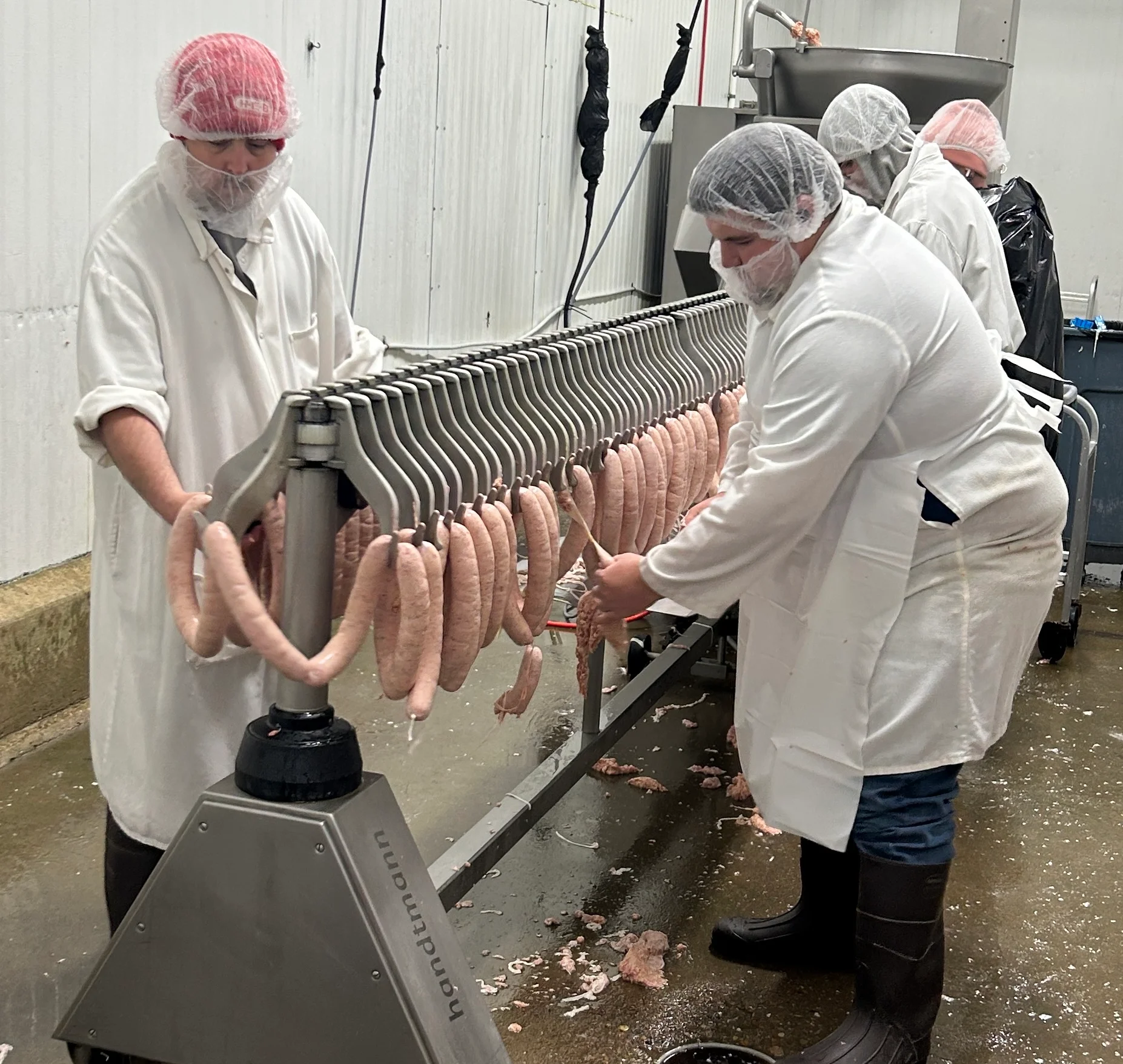 Workers preparing sausages in a meat processing facility