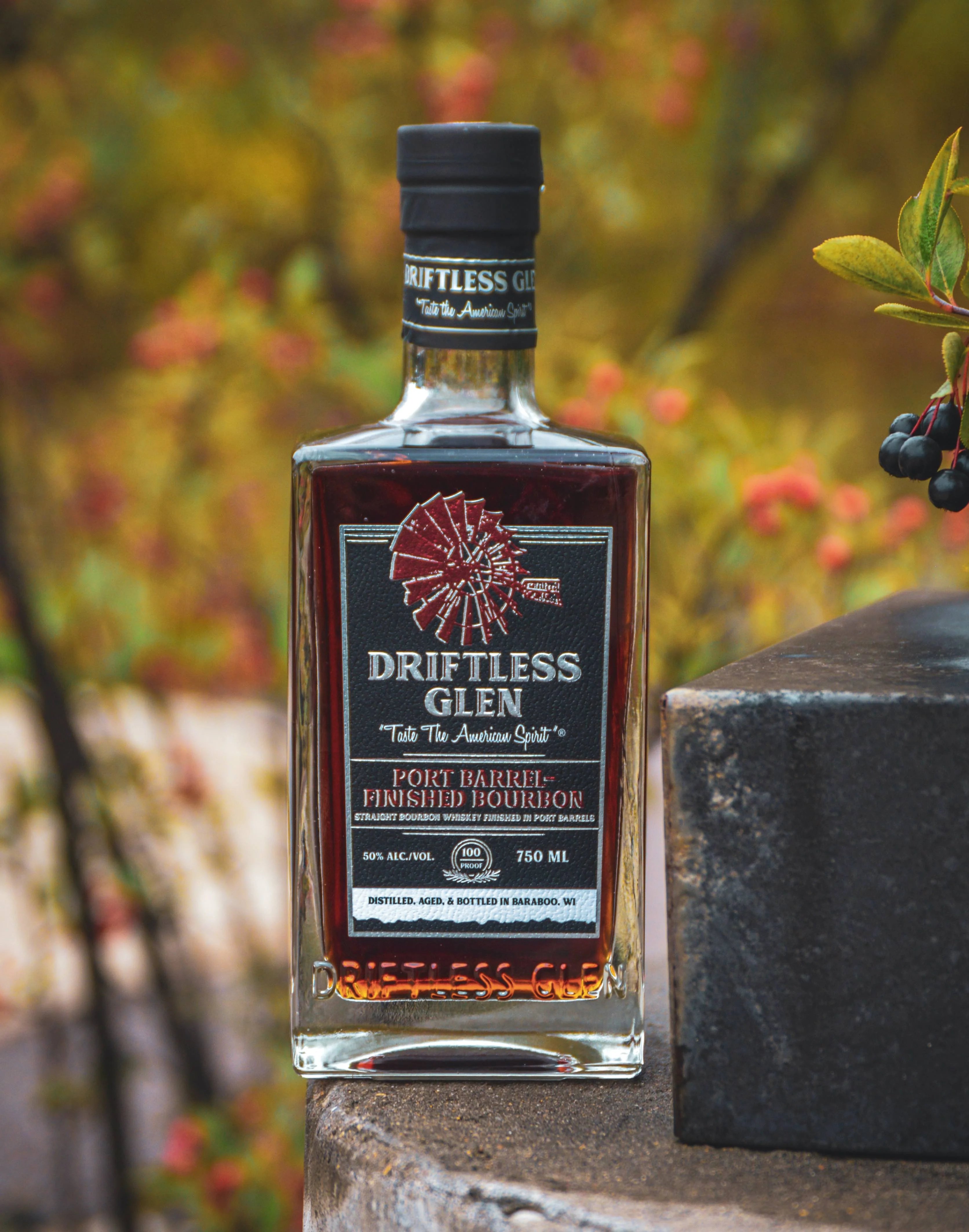 A dark purple label on a bottle of whiskey features the Port-Finished Bourbon with berries and red bushes around the outside of the image