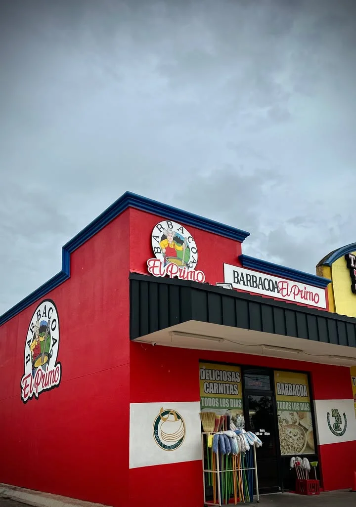 An exterior view of a restaurant building, showcasing a vibrant red facade and signage for a barbacoa establishment.