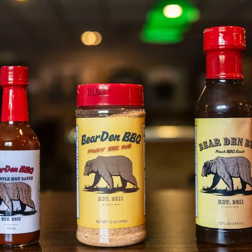 Bear Den BBQ sauces and rubs on a wooden table