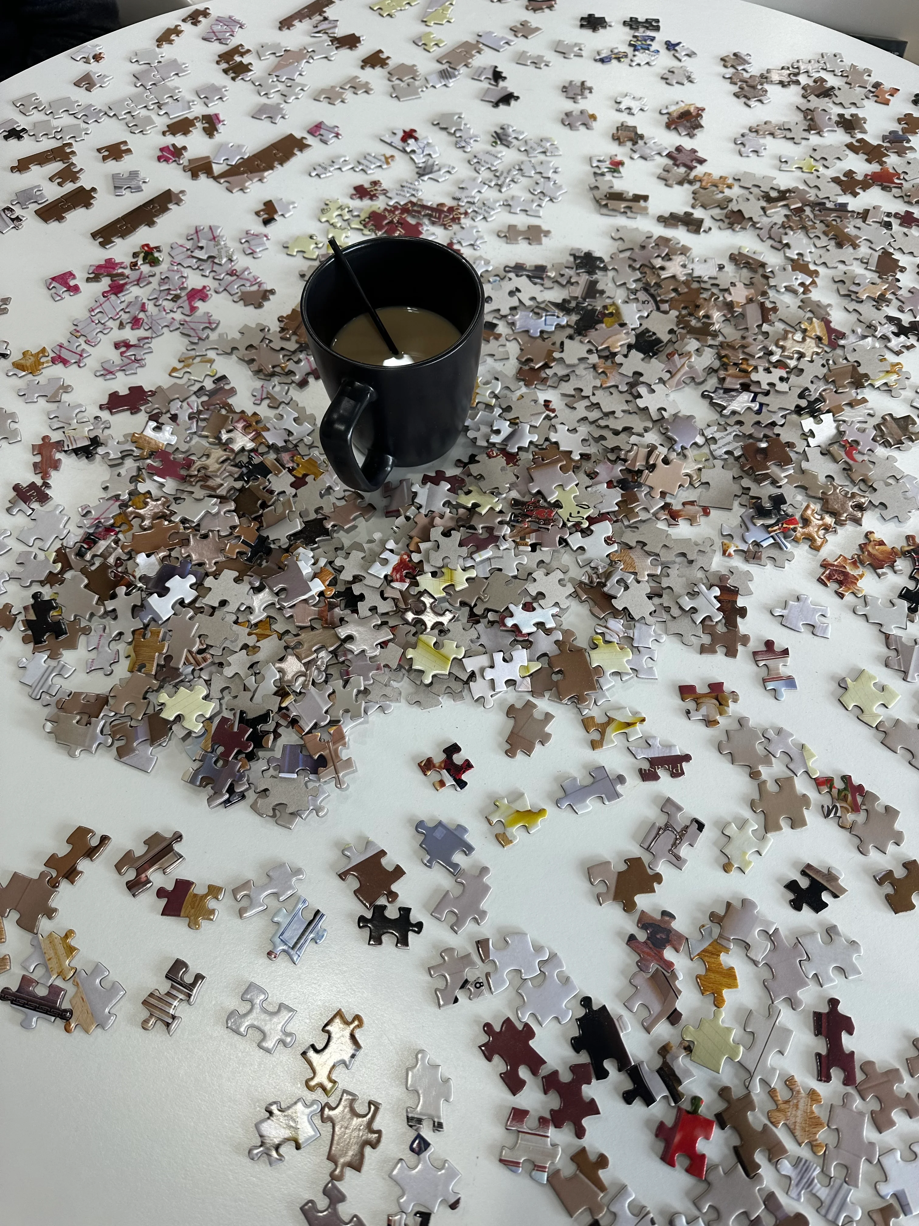 Coffee cup on a table scattered with jigsaw puzzle pieces