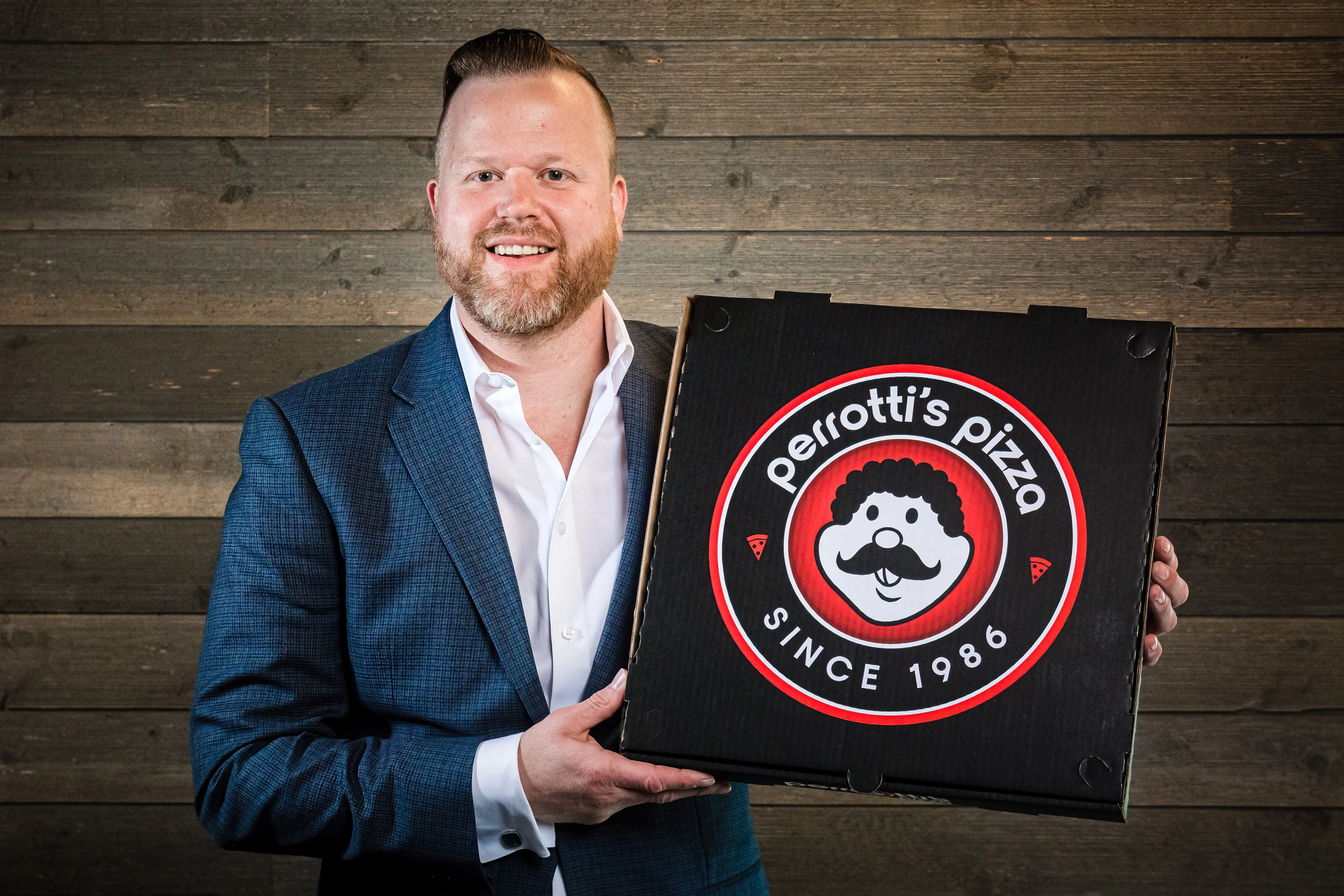 Owner presenting Perrotti's Pizza box with logo