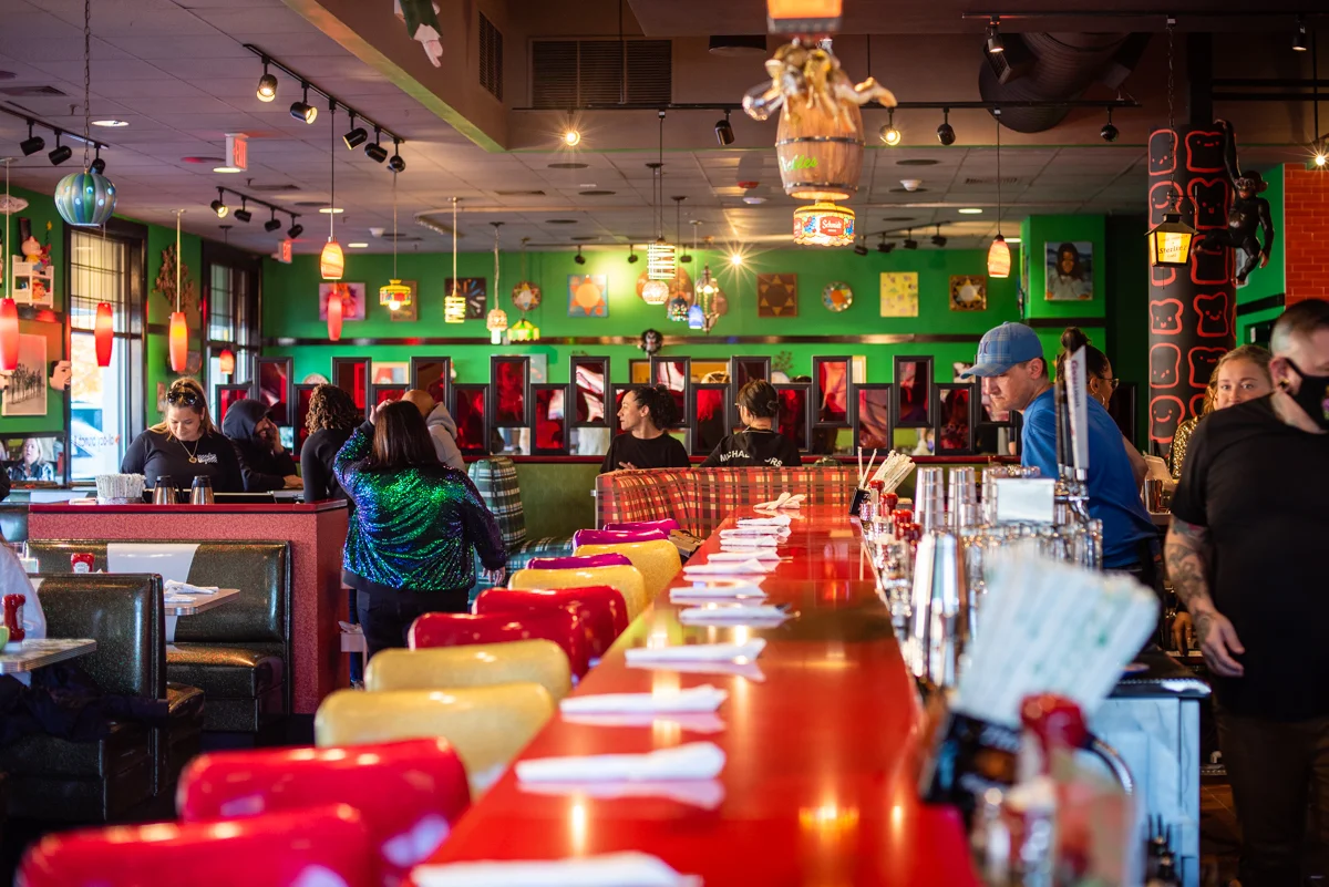Vibrant retro restaurant interior with colorful booths and busy diner counter