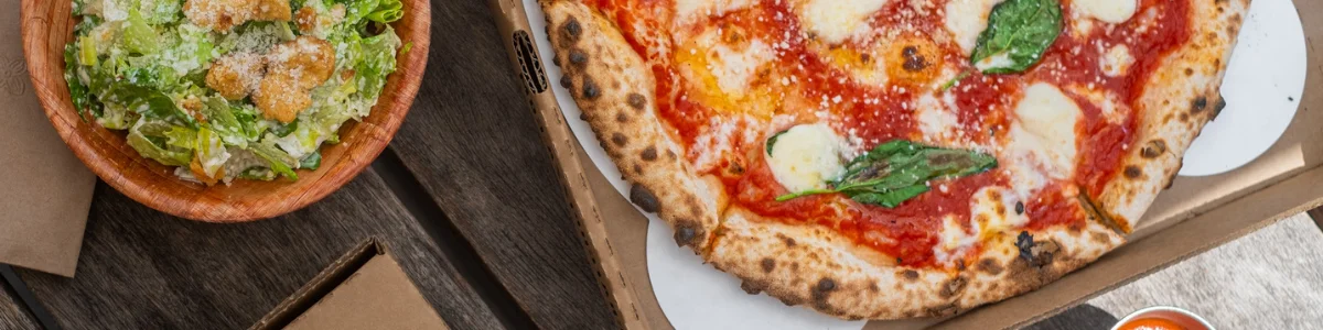 Margherita pizza with fresh basil and a side Caesar salad