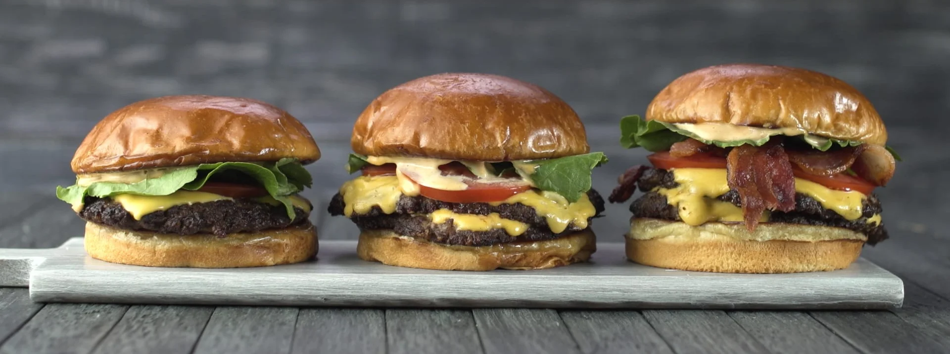 Gourmet cheeseburgers on a wooden platter