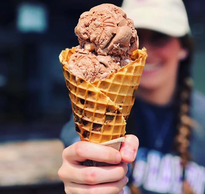 Delicious ice cream cone topped with whipped cream