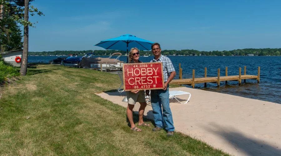 Couple holding a sign at a lakeside property with a dock