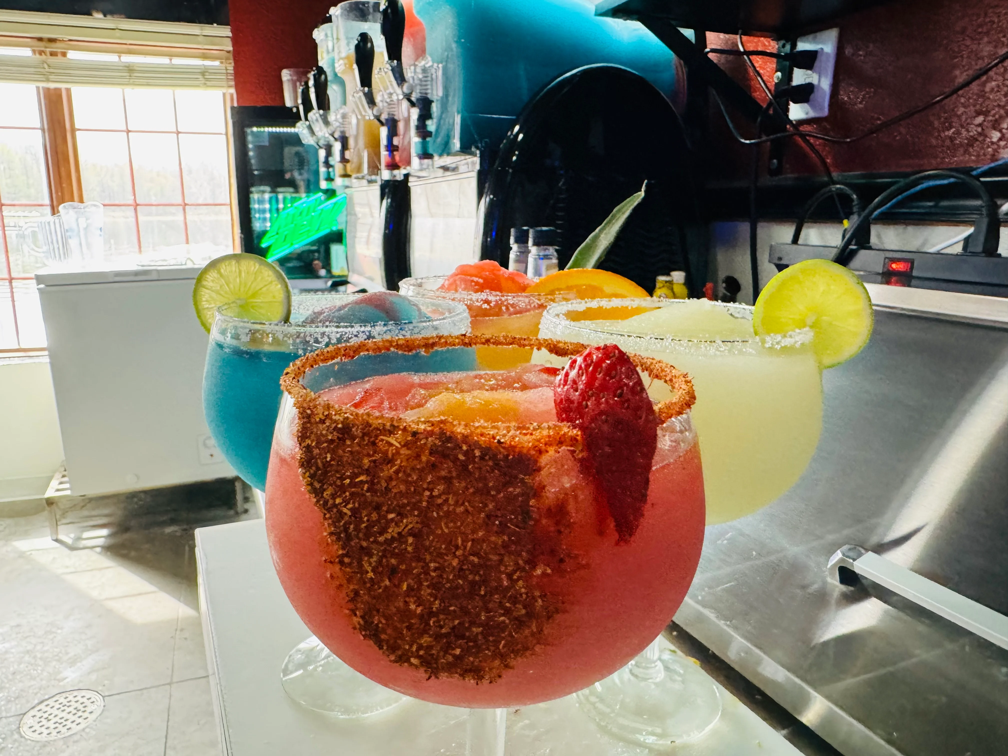 Colorful cocktails in large glasses at a vibrant bar